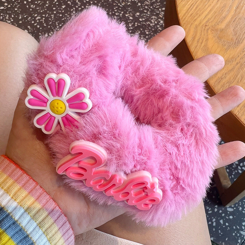 A woman's hand holding four pink fuzzy scrunchies, showcasing their soft texture and stylish design.