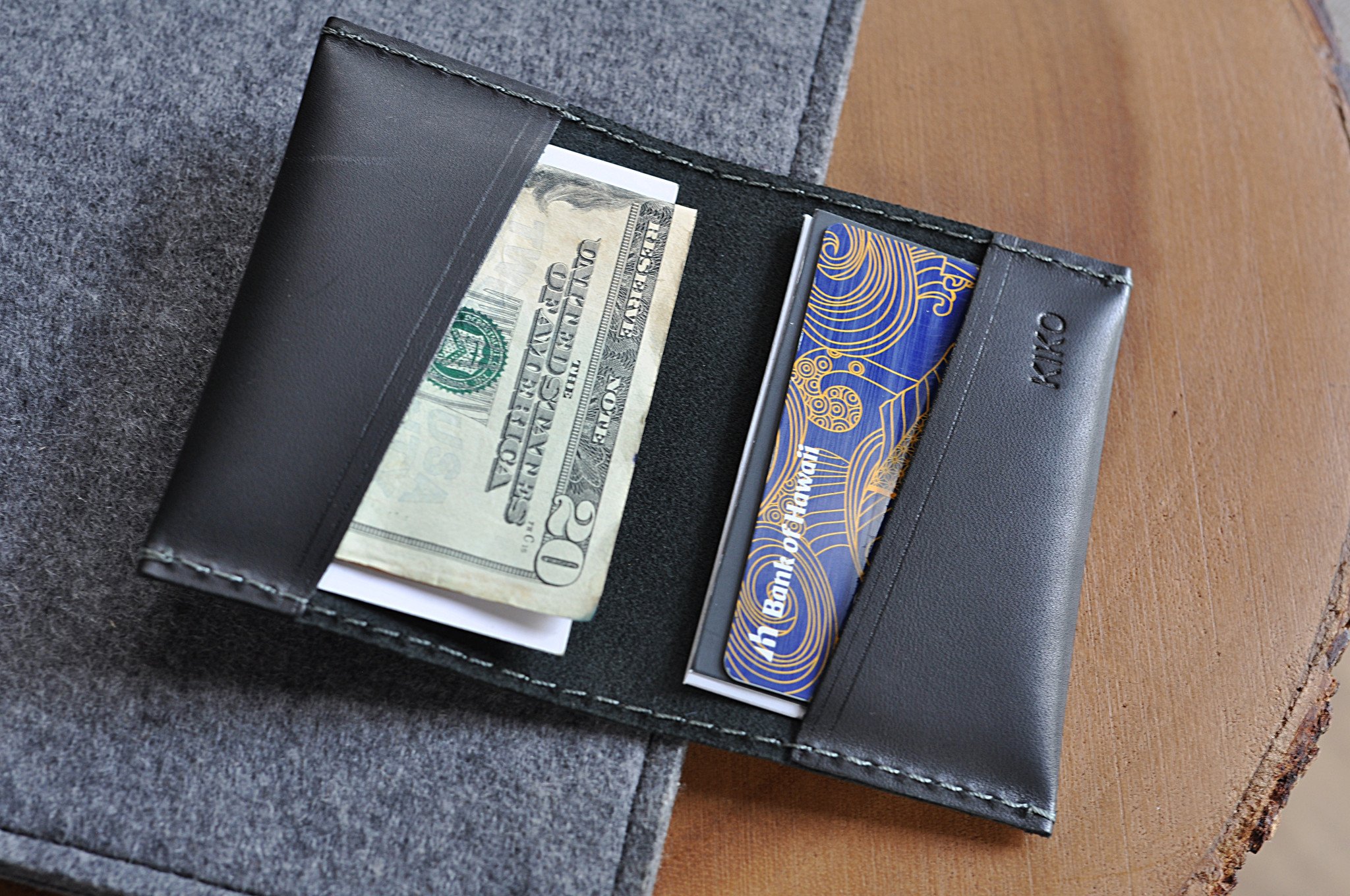 Two Fold Card Case made of premium black leather with grey stitching, featuring two slots for cards or notes.