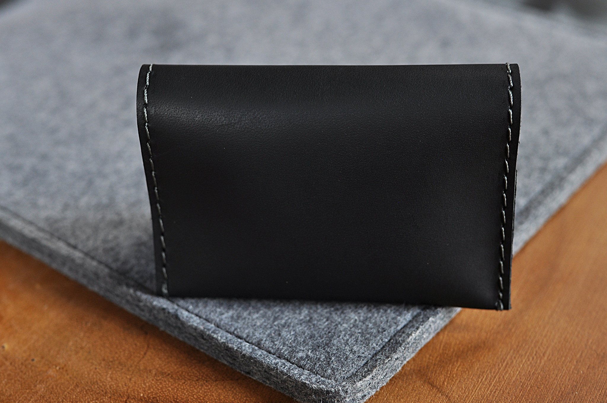 Two Fold Card Case made of premium black leather with grey stitching, featuring two slots for cards or notes.