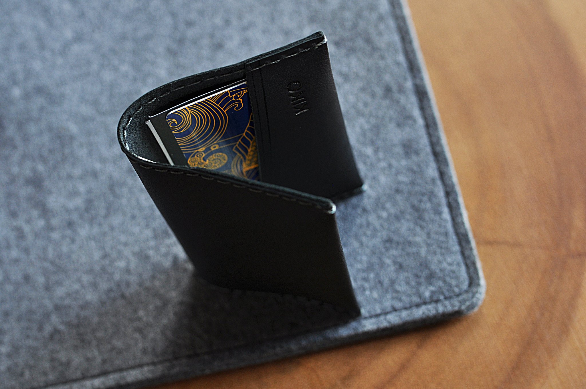 Two Fold Card Case made of premium black leather with grey stitching, featuring two slots for cards or notes.