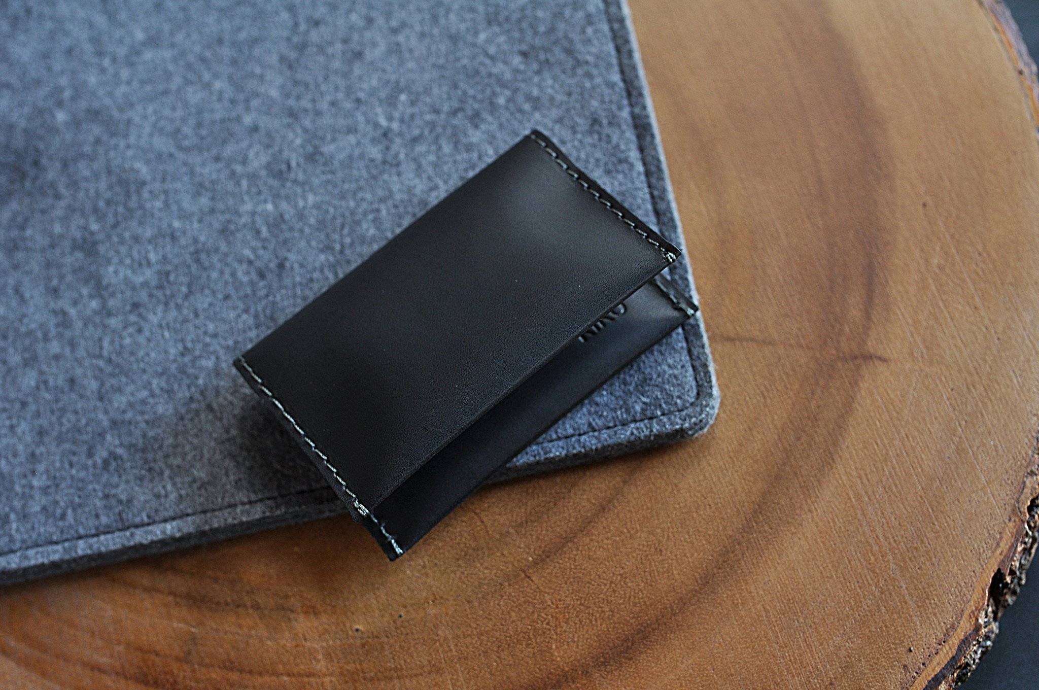 Two Fold Card Case made of premium black leather with grey stitching, featuring two slots for cards or notes.