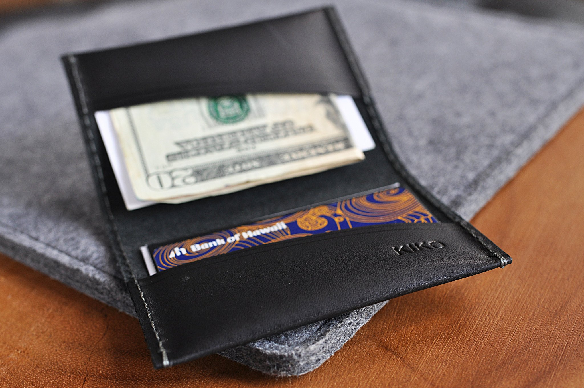 Two Fold Card Case made of premium black leather with grey stitching, featuring two slots for cards or notes.