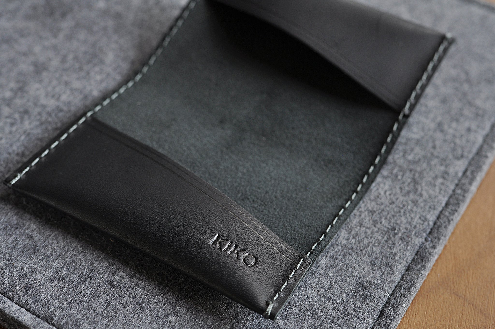 Two Fold Card Case made of premium black leather with grey stitching, featuring two slots for cards or notes.