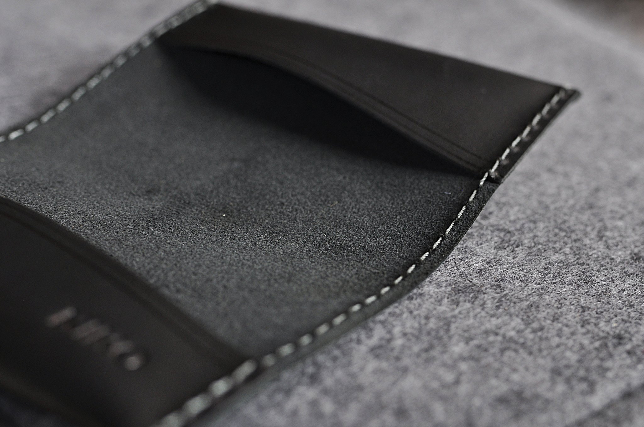 Two Fold Card Case made of premium black leather with grey stitching, featuring two slots for cards or notes.