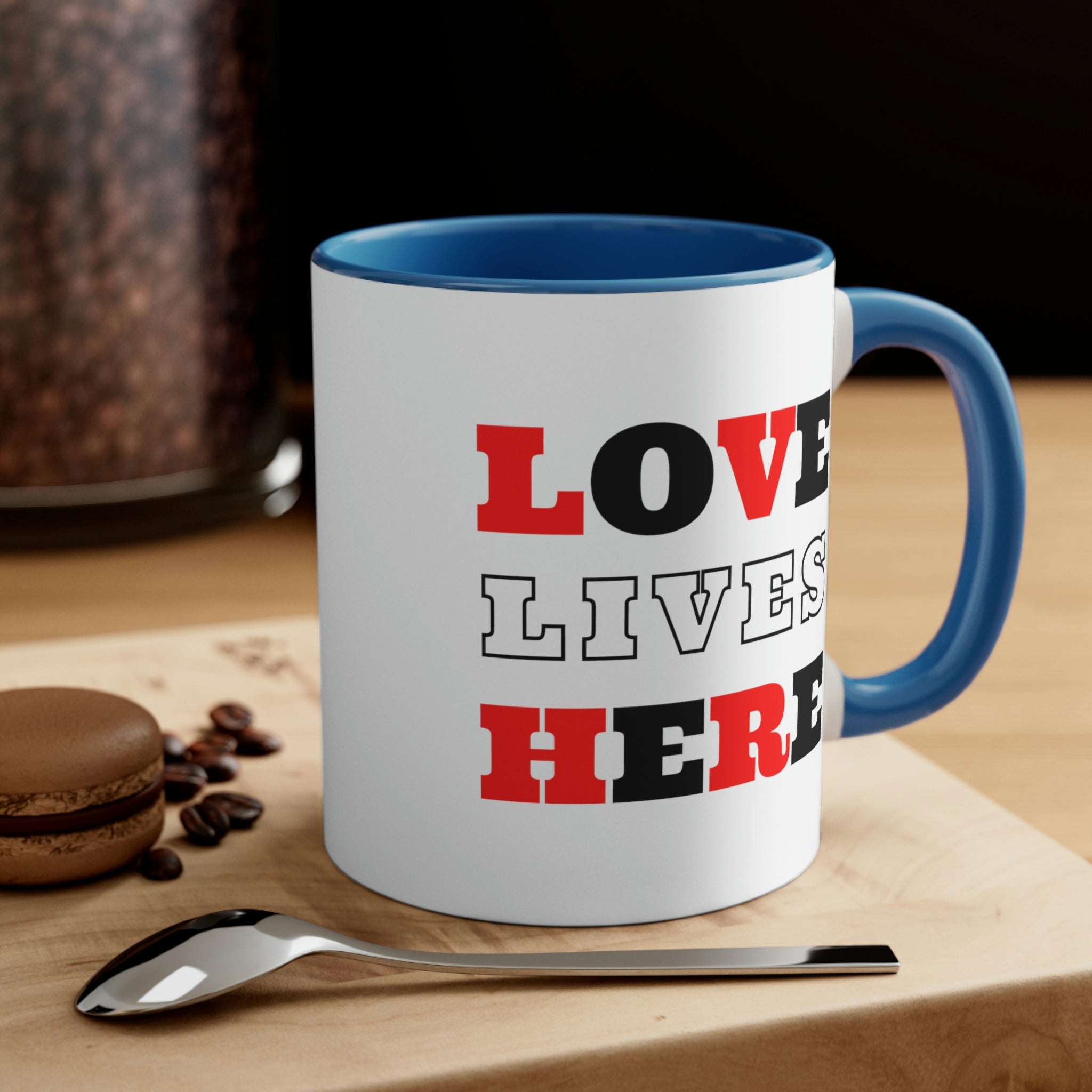 Two-tone ceramic mug with a white exterior and colored interior, featuring a comfortable C-handle and the phrase 'Love Lives Here'.