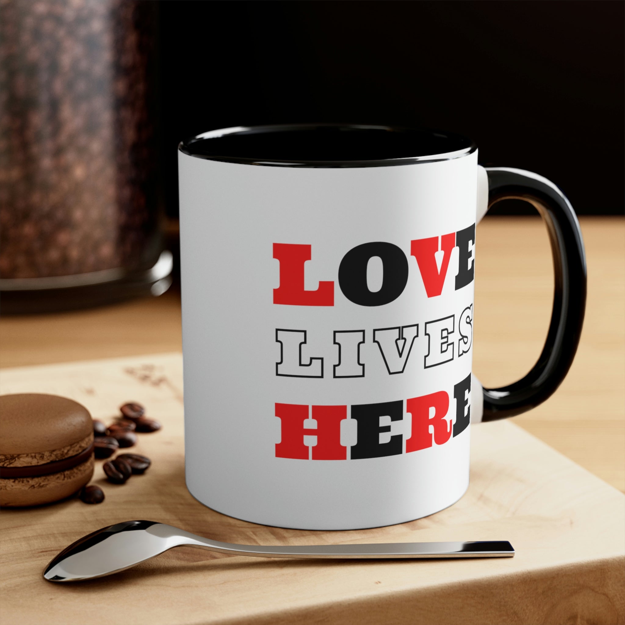 Two-tone ceramic mug with a white exterior and colored interior, featuring a comfortable C-handle and the phrase 'Love Lives Here'.