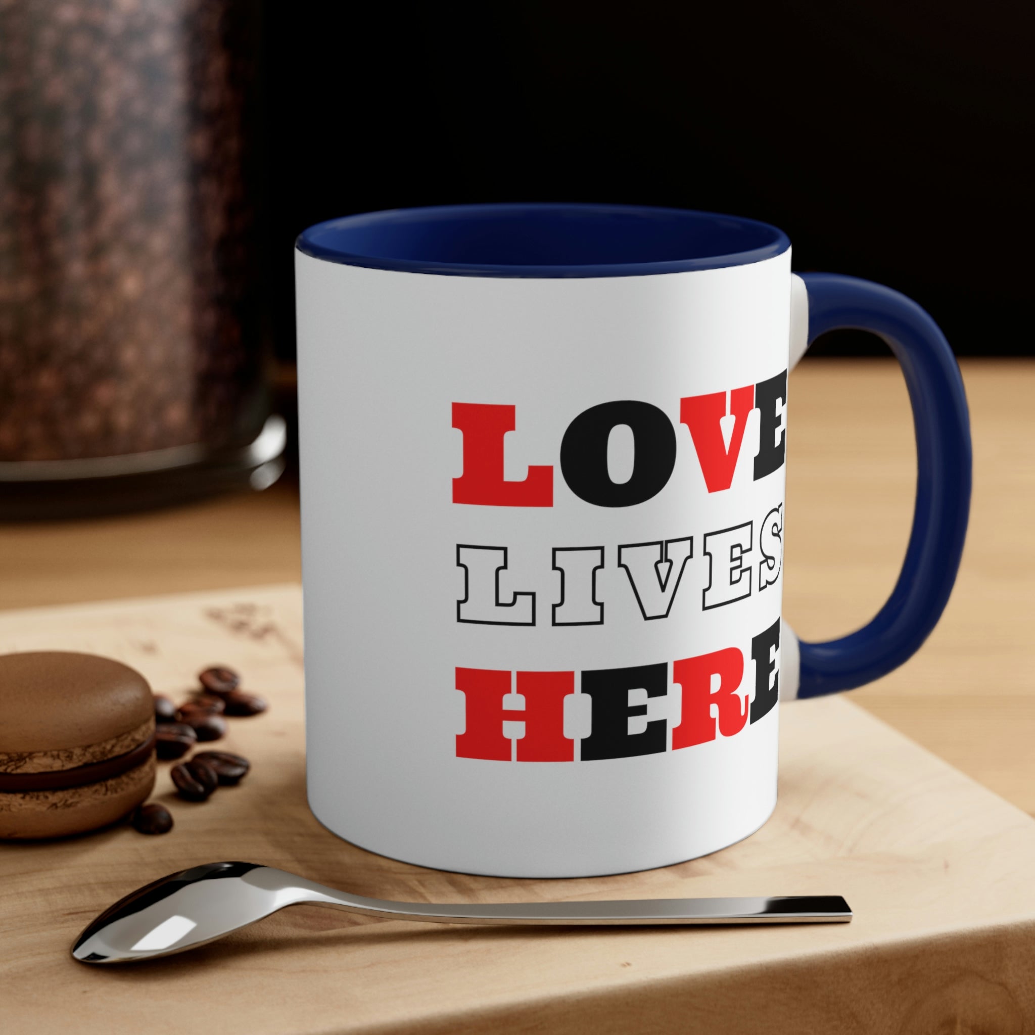 Two-tone ceramic mug with a white exterior and colored interior, featuring a comfortable C-handle and the phrase 'Love Lives Here'.