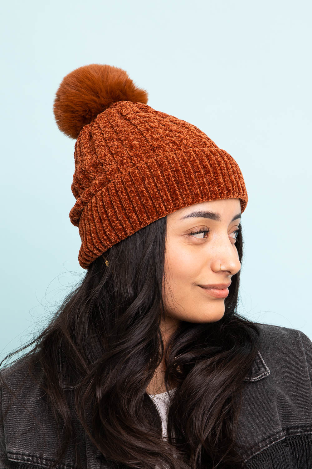 A stylish Velvet Cable Knit Pom Beanie in a rich color, featuring a textured cable knit design and a fluffy pom pom on top.