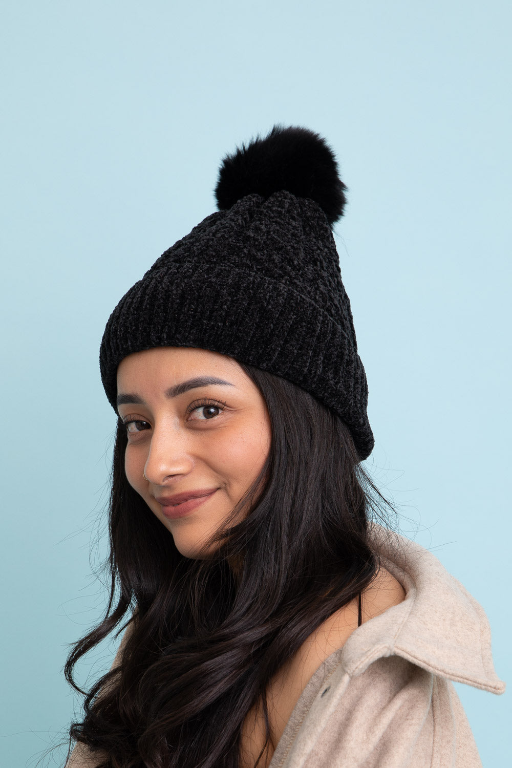 A stylish Velvet Cable Knit Pom Beanie in a rich color, featuring a textured cable knit design and a fluffy pom pom on top.