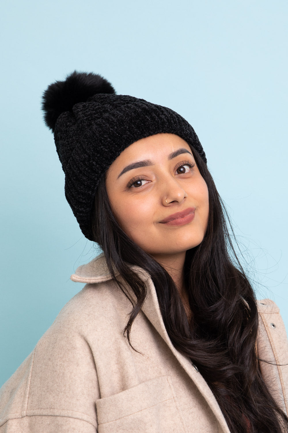 A stylish Velvet Cable Knit Pom Beanie in a rich color, featuring a textured cable knit design and a fluffy pom pom on top.