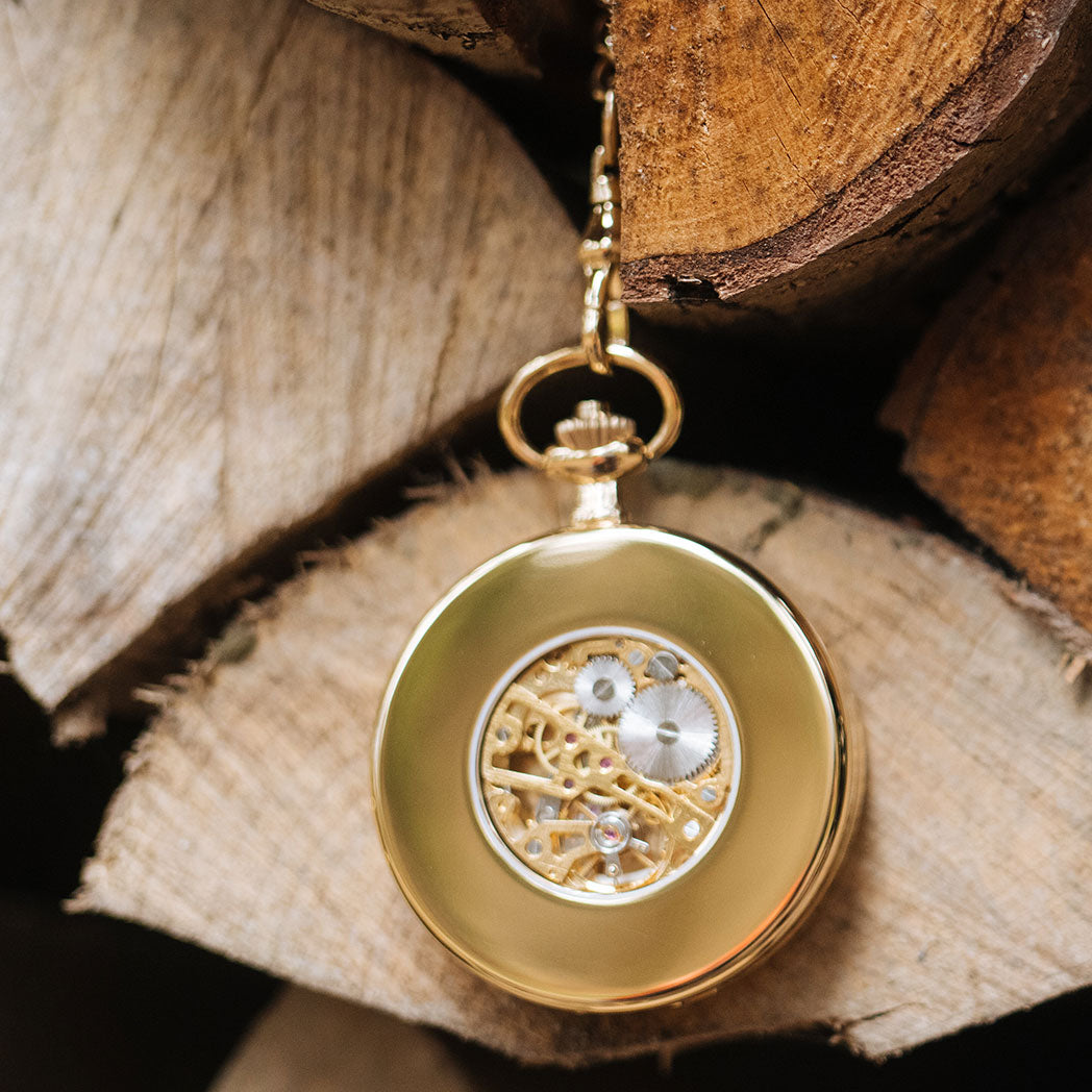 Waidzeit Franz Rudolf Skeleton pocket watch in gold with Roman numerals and root wood finish, showcasing intricate movement through glass windows.