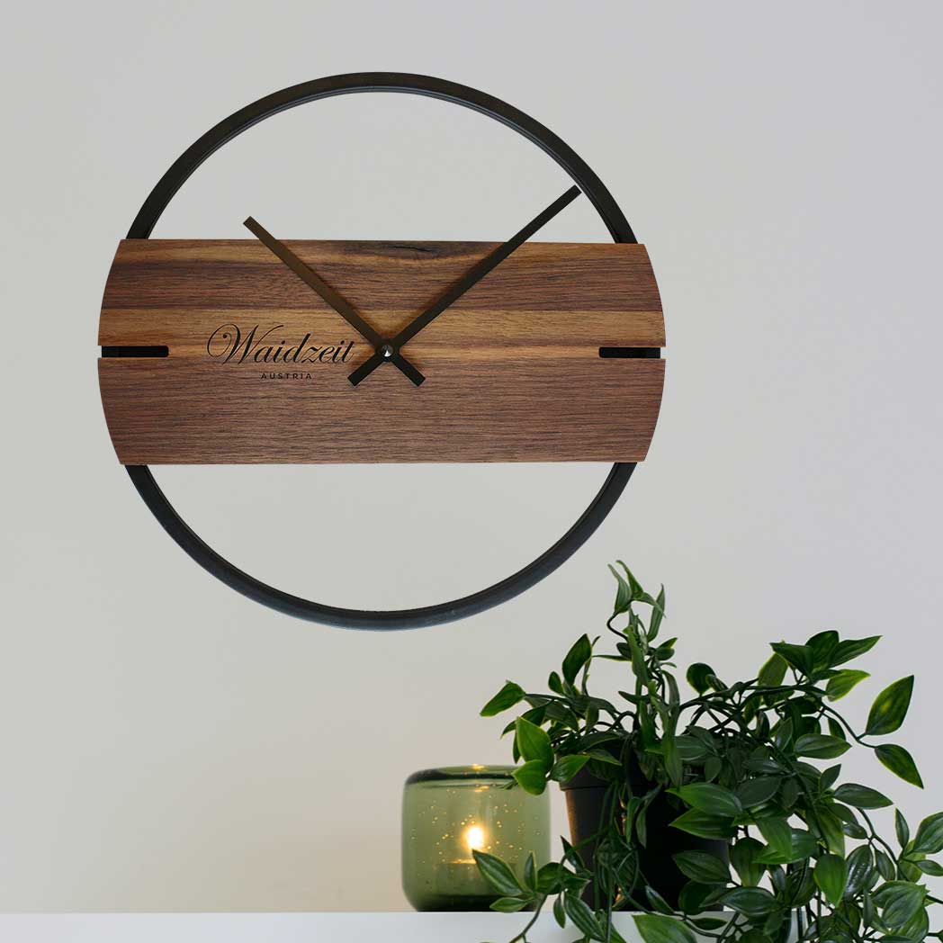 Waidzeit Novum wall clock in walnut with black metal ring, showcasing elegant Scandinavian design and natural wood grain.