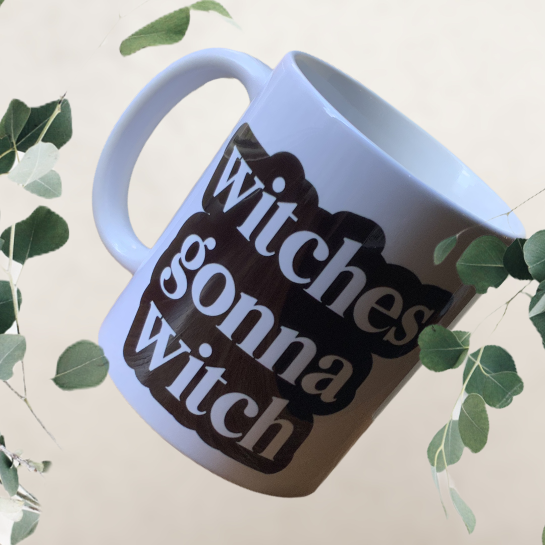 A whimsical 11oz ceramic mug with 'Witches Gonna Witch' design printed on both sides, perfect for hot or cold beverages.