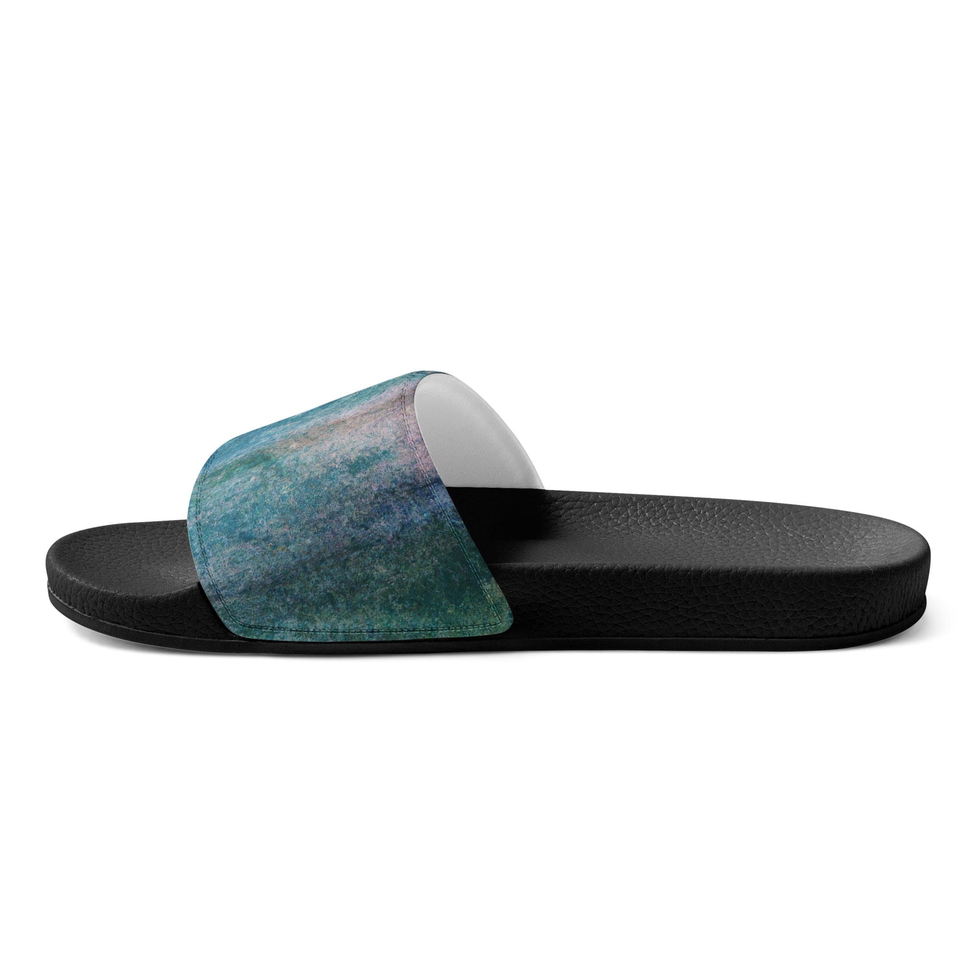 A pair of women's slides featuring a blue hue watercolor abstract print, showcasing a cushioned faux leather upper strap and textured footbed.