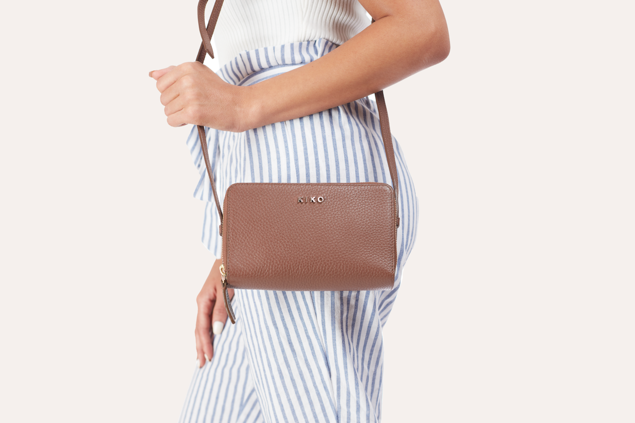 Zip Around Crossbody Pebble bag made of genuine pebble leather, featuring two zipper compartments and an adjustable shoulder strap.