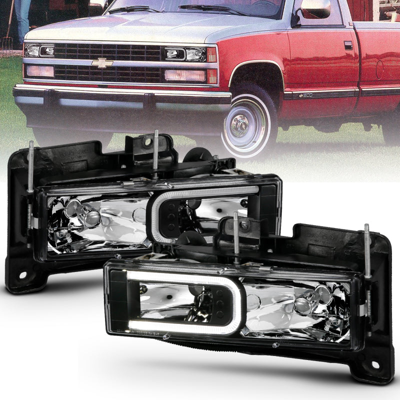 ANZO 1999-2000 Cadillac Escalade Crystal Headlights with a sleek black light bar design, enhancing vehicle visibility and style.