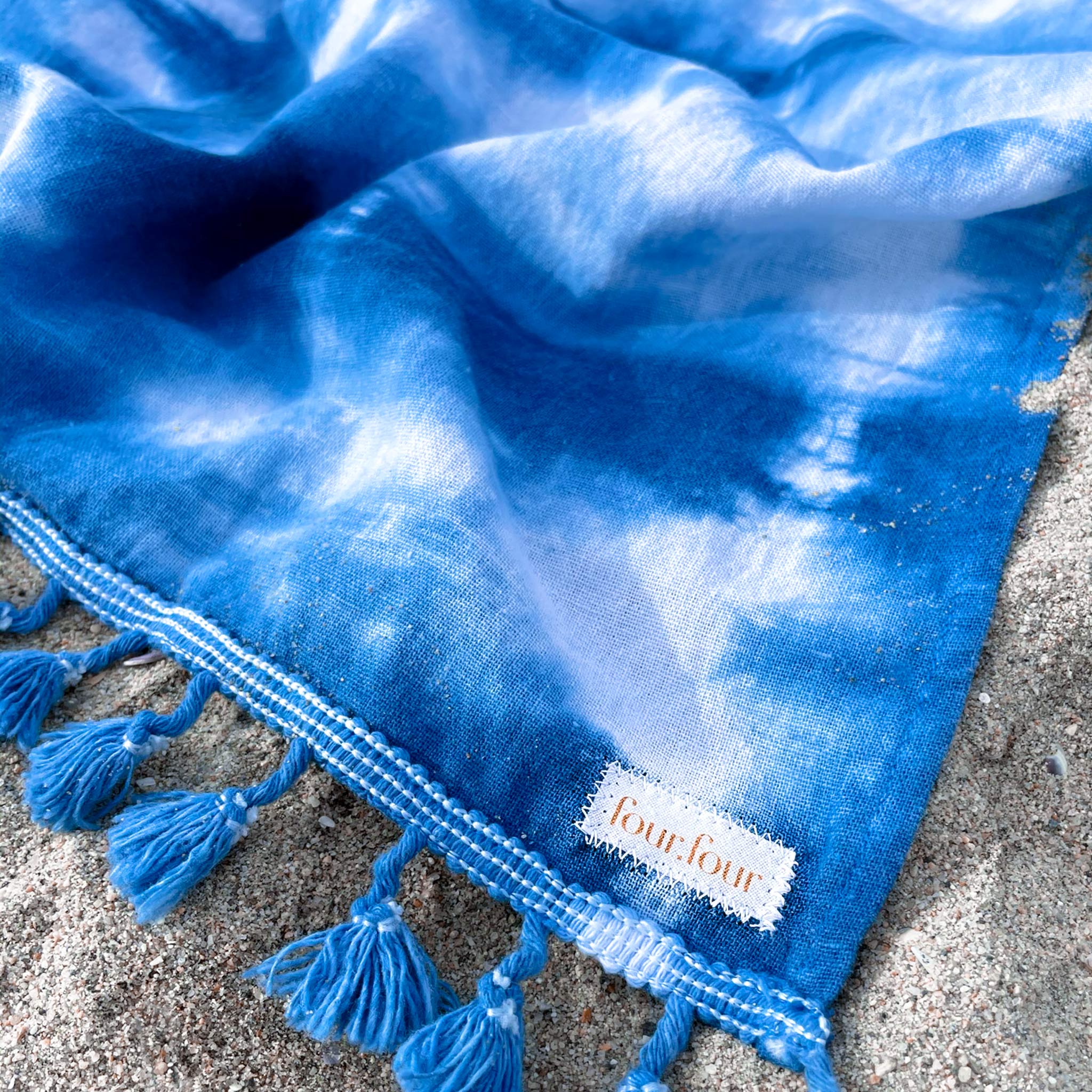 A unique indigo-dyed beach blanket made from soft cotton, showcasing beautiful patterns and vibrant colors, perfect for beach outings or home decor.