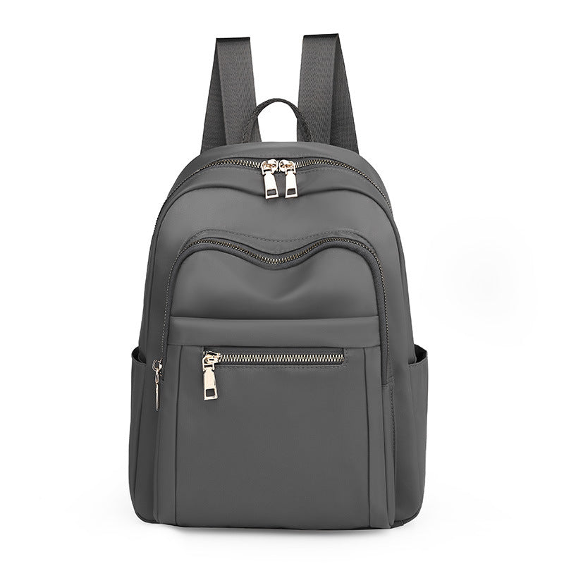 A stylish Oxford cloth backpack in plain design, featuring multiple compartments and a zipper opening, ideal for travel and daily use.