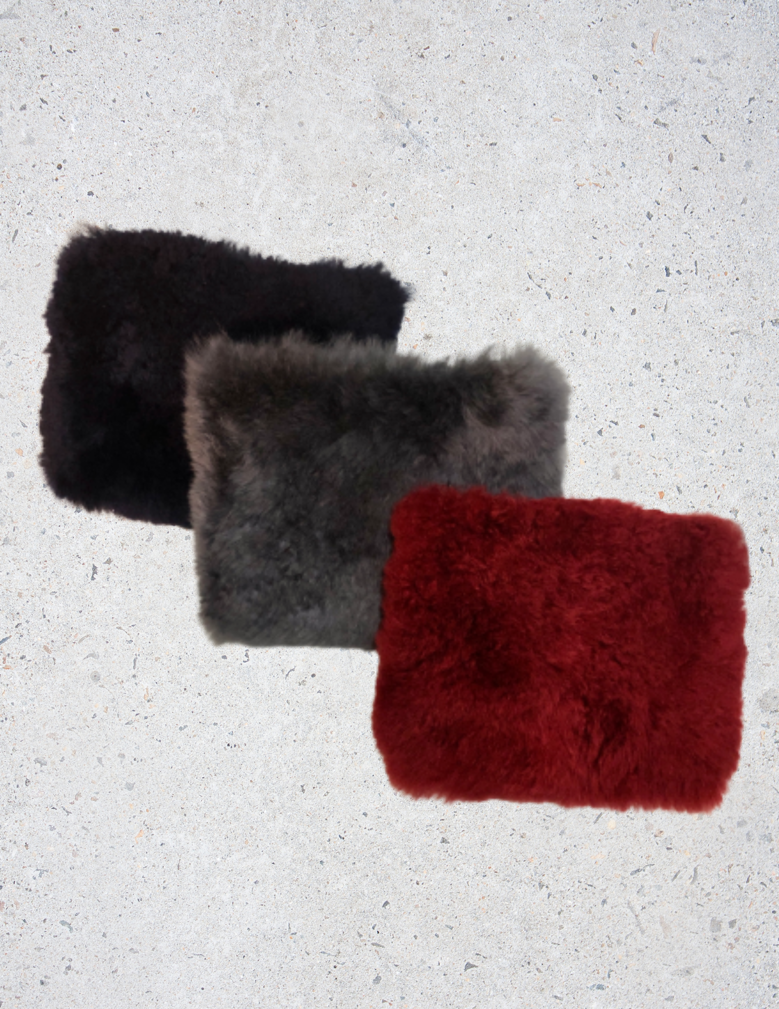 A luxurious Fur Wristlet made from soft baby alpaca fur, featuring a leather wristlet strap and zipper closure, available in Maroon, Navy, and Dark Grey.