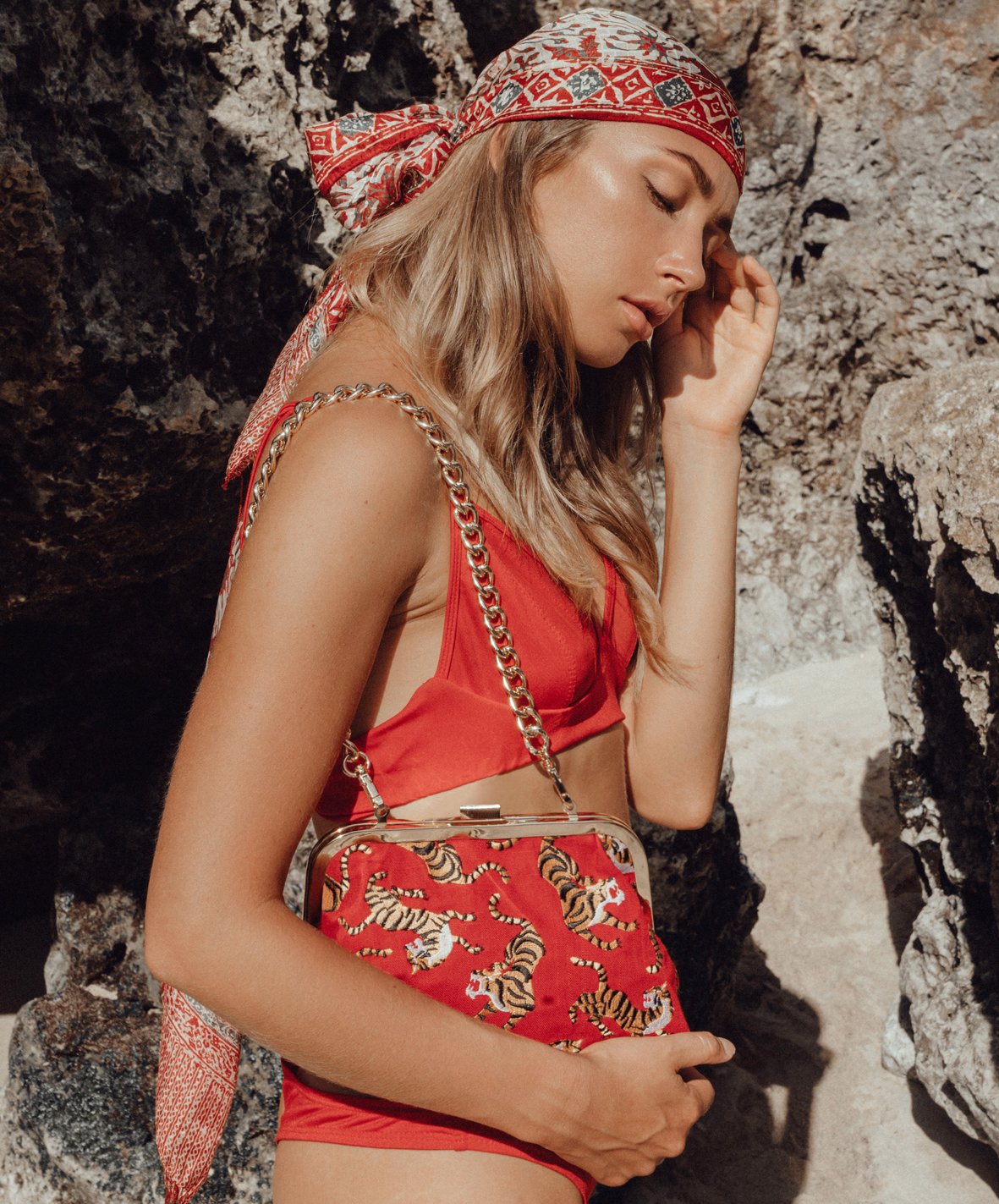 A vibrant red clutch featuring intricate cotton embroidery, gold metal chain strap, and dimensions of 8.75" W x 6.2" H x 2.75" D, symbolizing Sumatran tiger conservation.