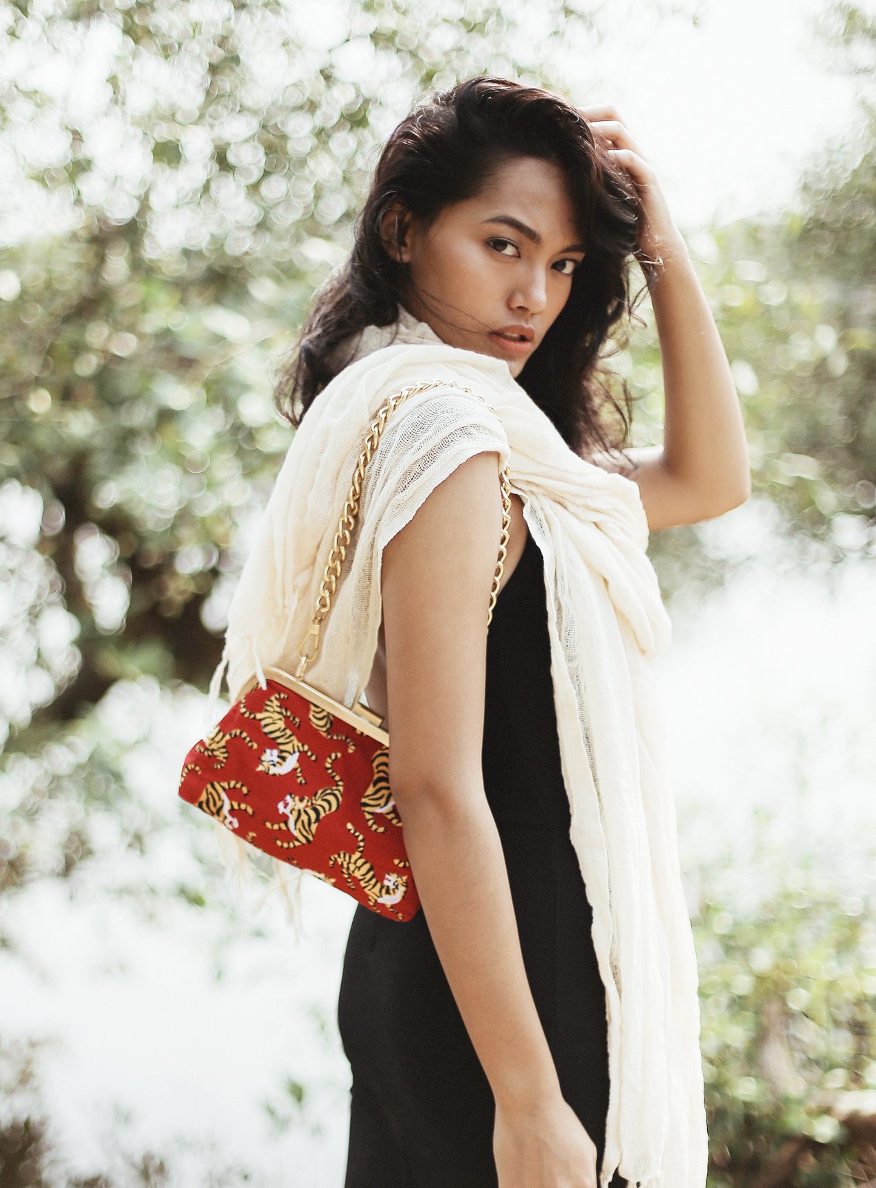 A vibrant red clutch featuring intricate cotton embroidery, gold metal chain strap, and dimensions of 8.75" W x 6.2" H x 2.75" D, symbolizing Sumatran tiger conservation.