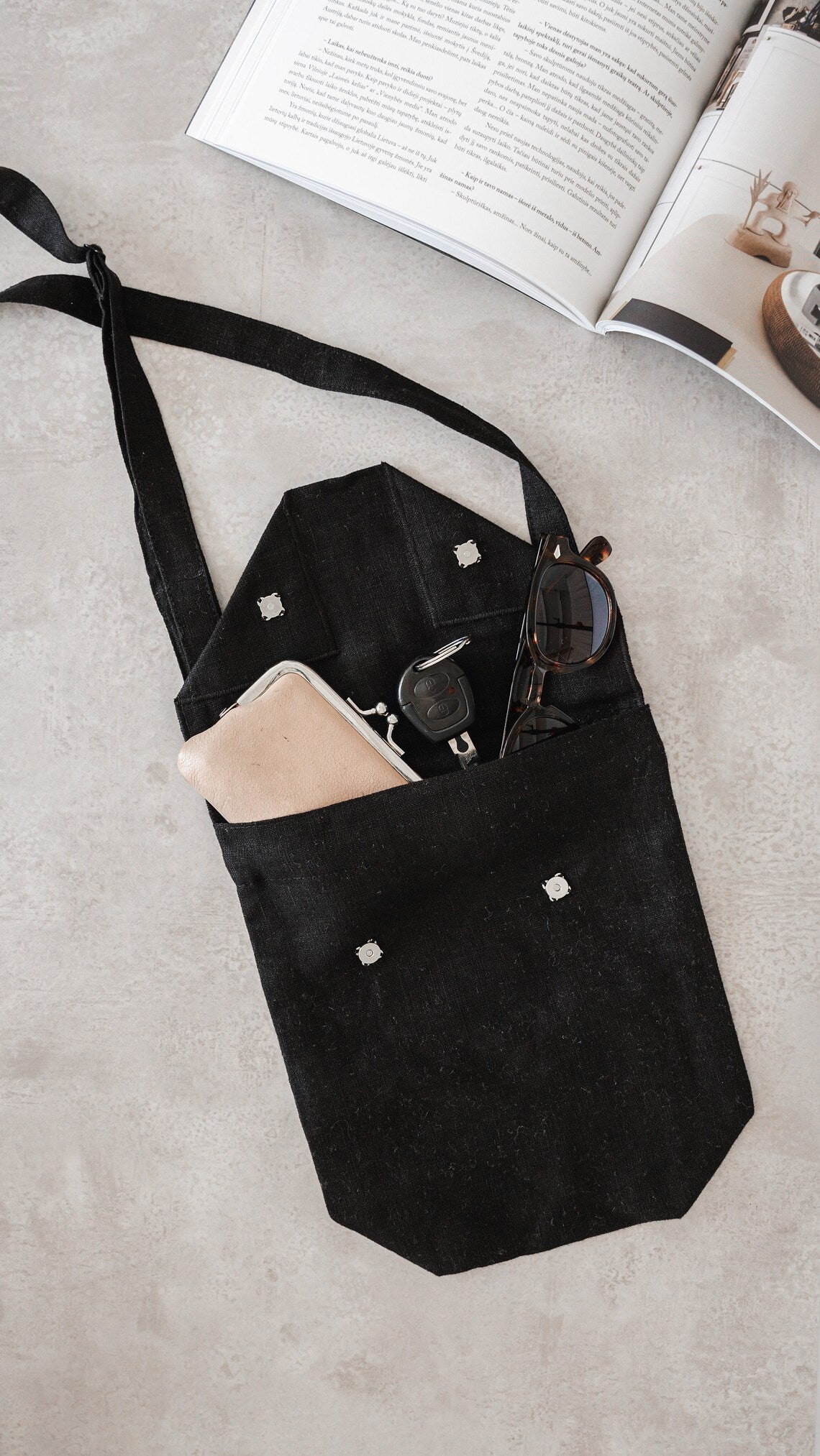 Black linen shoulder bag featuring coconut buttons and an adjustable strap, showcasing its elegant design and quality craftsmanship.