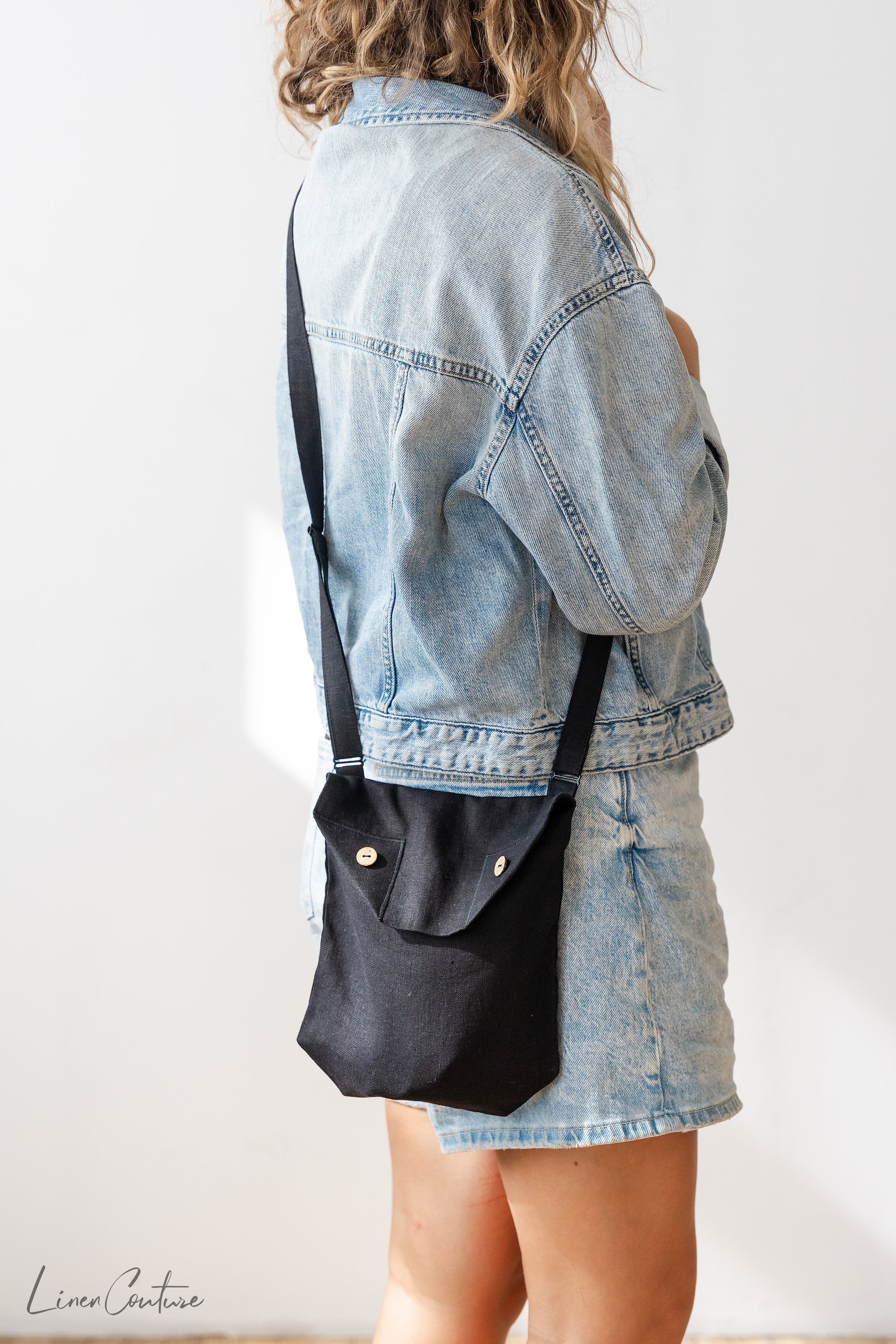 Black linen shoulder bag featuring coconut buttons and an adjustable strap, showcasing its elegant design and quality craftsmanship.