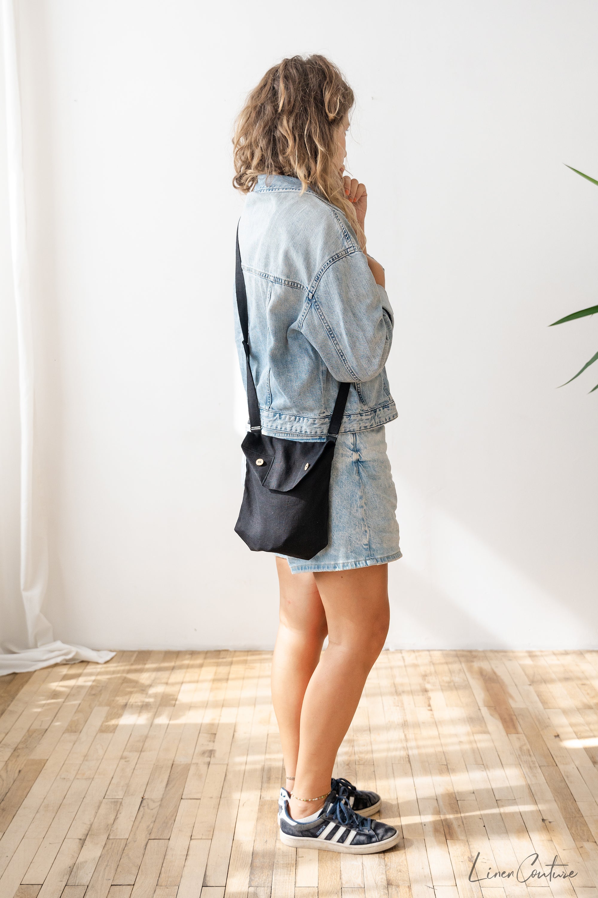 Black linen shoulder bag featuring coconut buttons and an adjustable strap, showcasing its elegant design and quality craftsmanship.