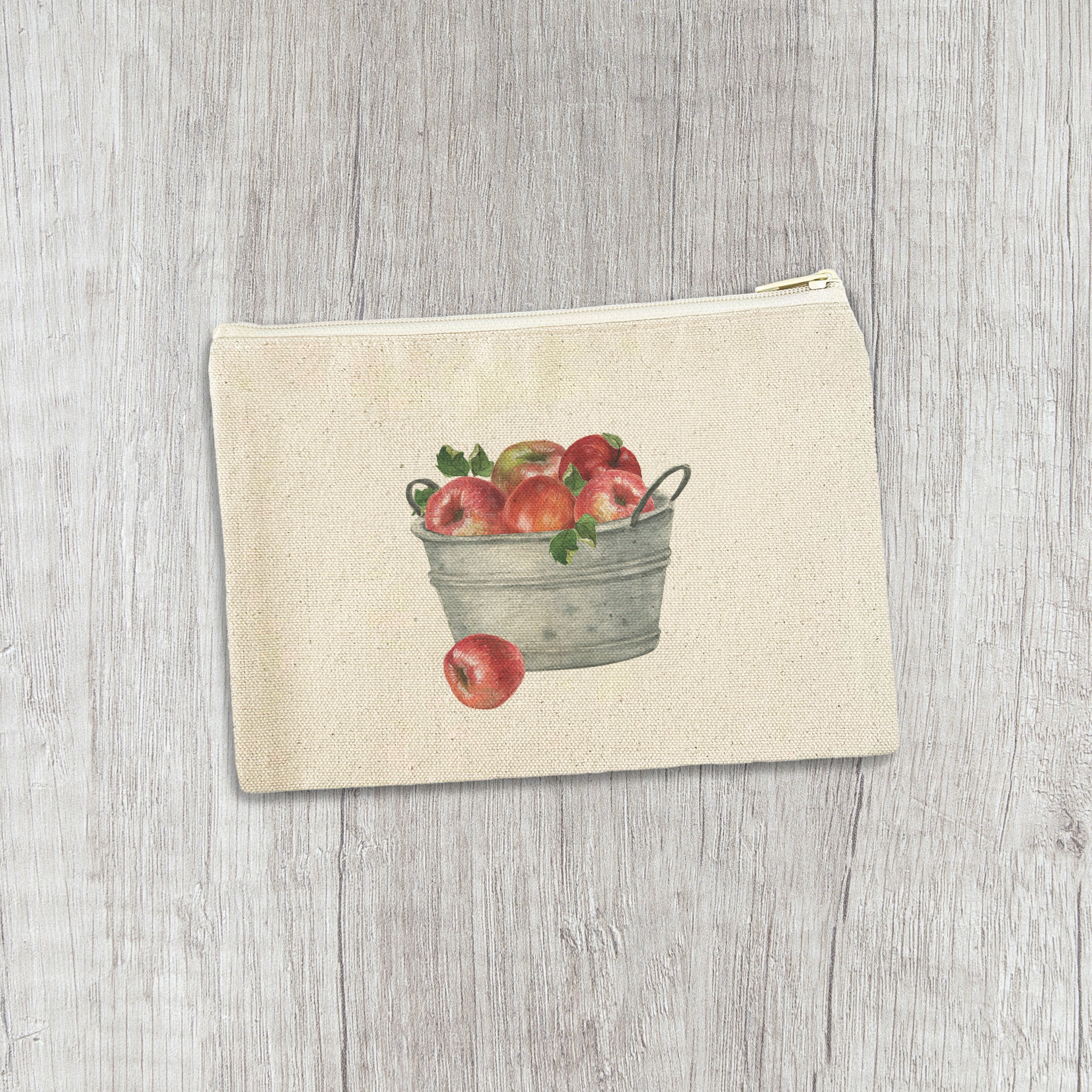 A colorful canvas zipper pouch featuring a bucket of red apples design, showcasing its durable cotton material and natural zipper.