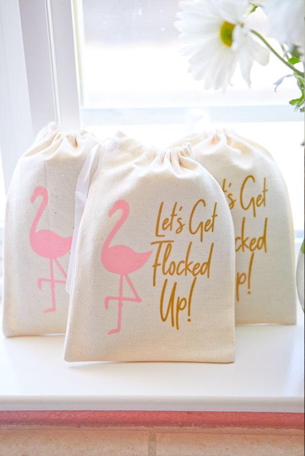 A vibrant canvas bag featuring a pink flamingo and glittery gold text that says 'Let's Get Flocked Up', perfect for hangover kits and party favors.