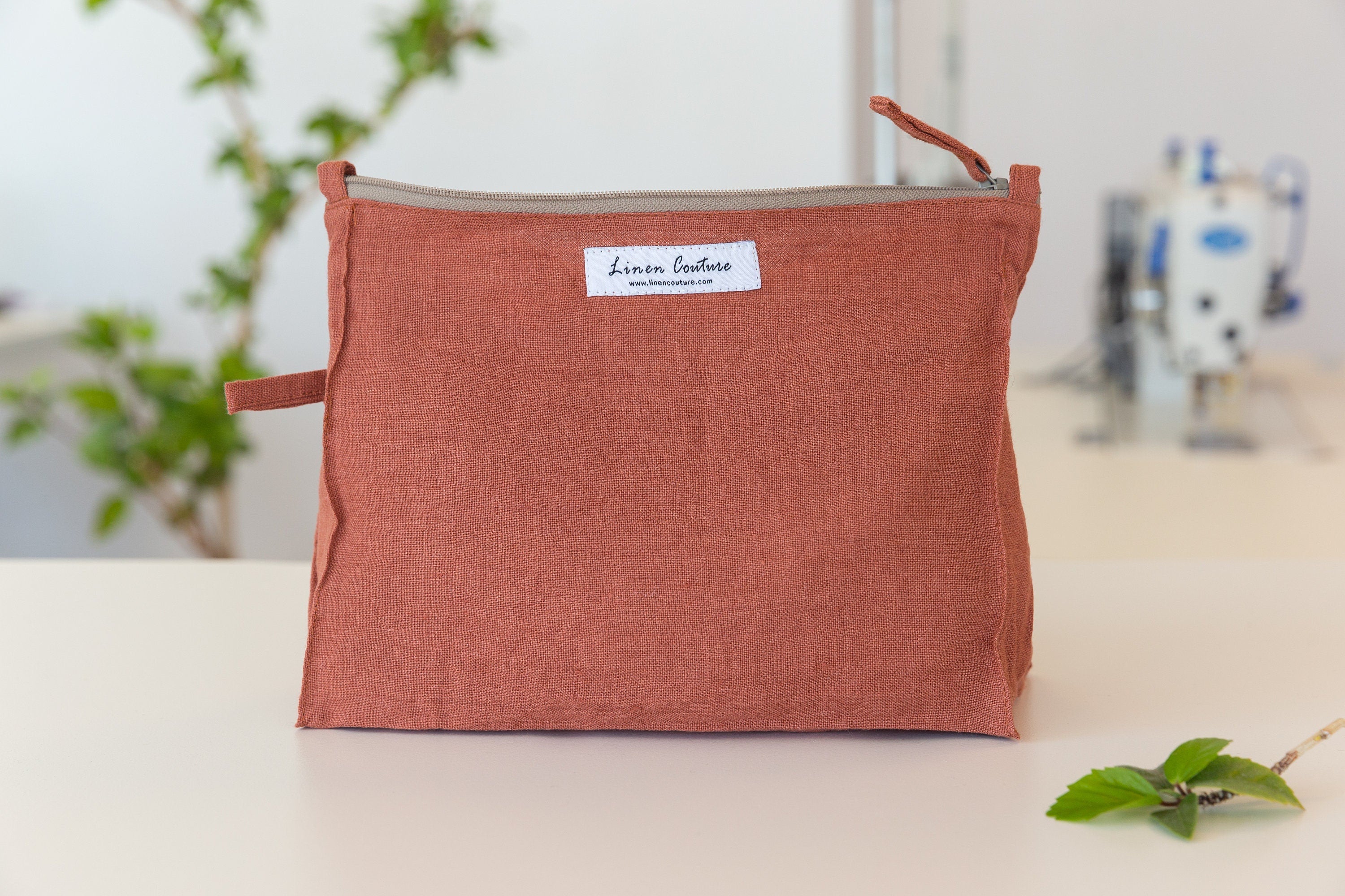 A large reddish brown linen cosmetic bag with zipper closure, showcasing its elegant design and soft texture, perfect for organizing essentials.