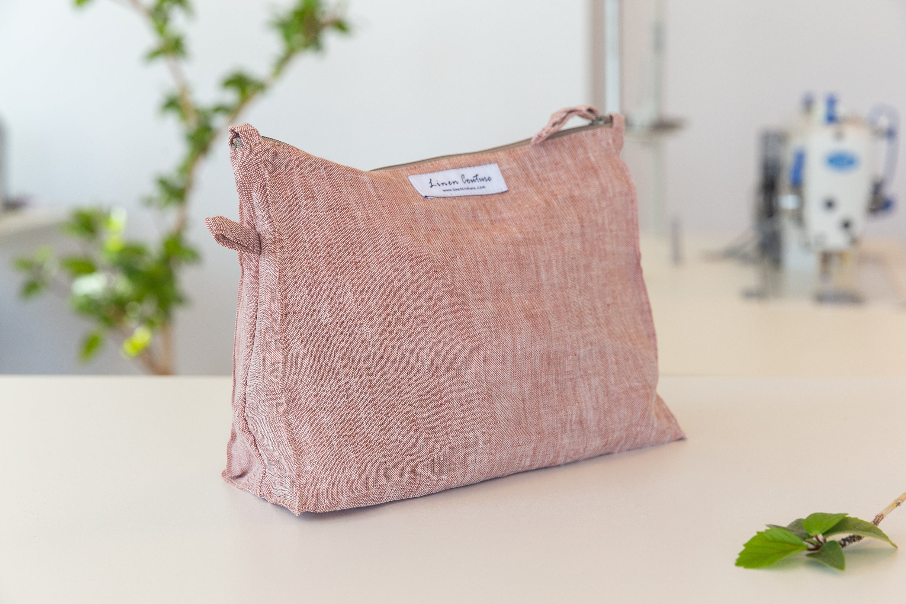 A large reddish brown linen cosmetic bag with zipper closure, showcasing its elegant design and soft texture, perfect for organizing essentials.