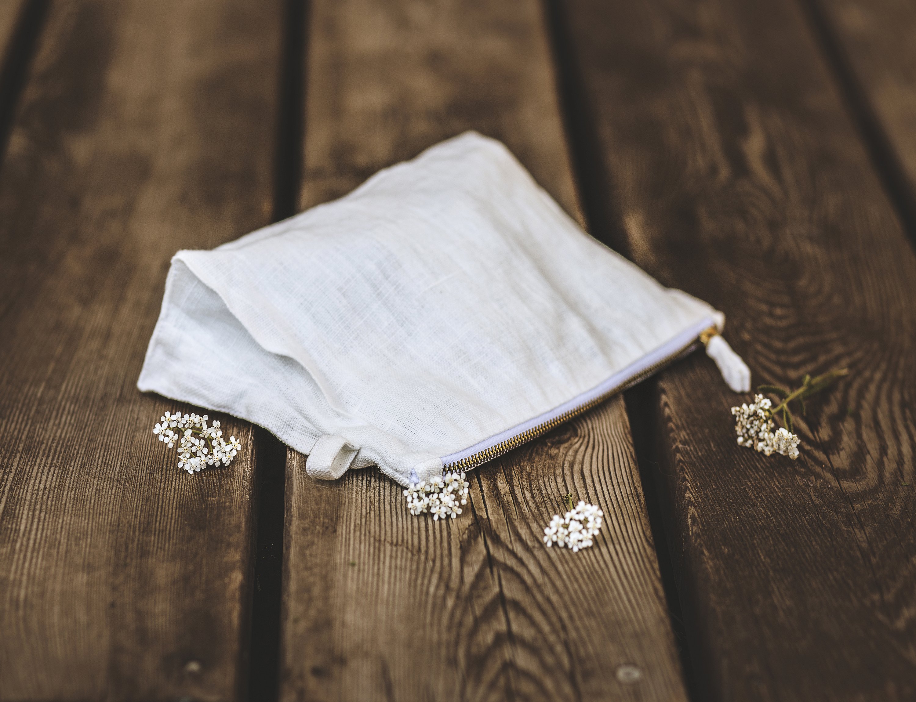 A stylish white linen pochette with zipper closure, showcasing its soft texture and practical design, ideal for toiletries and daily use.