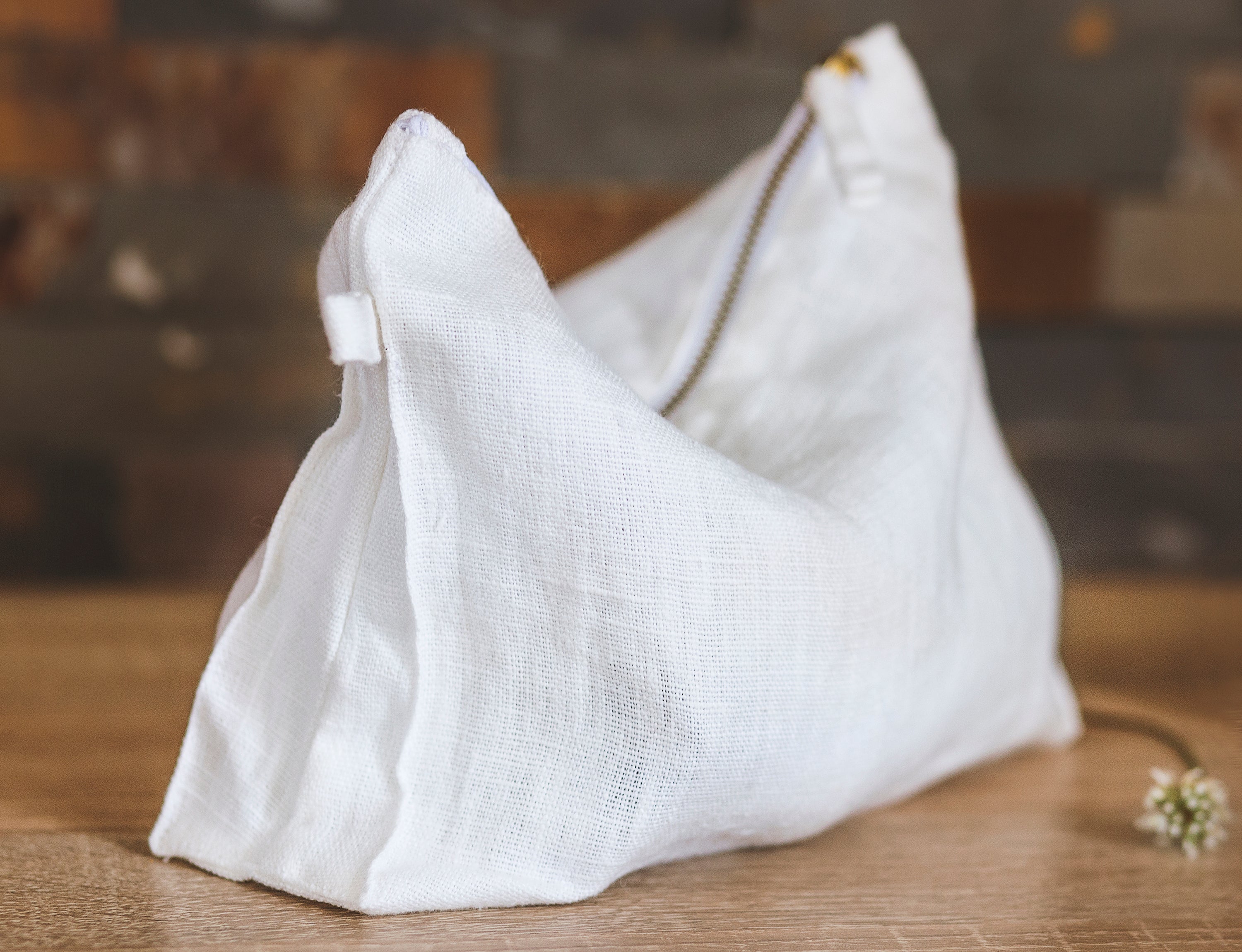 A stylish white linen pochette with zipper closure, showcasing its soft texture and practical design, ideal for toiletries and daily use.