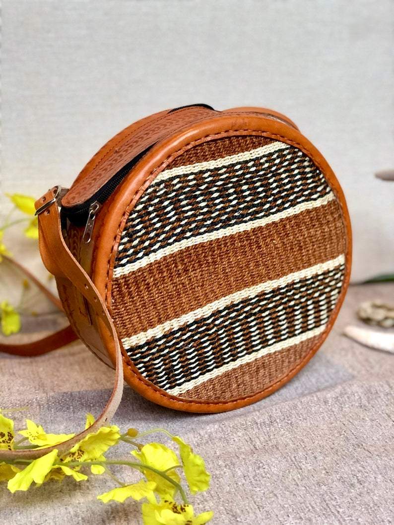 A beautifully handwoven African Round Sisal Sling Bag in brown, showcasing its unique round shape and natural fiber texture.