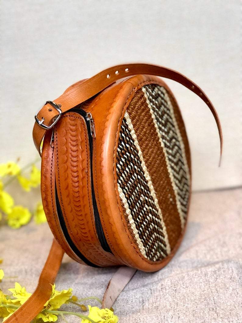 A beautifully handwoven African Round Sisal Sling Bag in brown, showcasing its unique round shape and natural fiber texture.