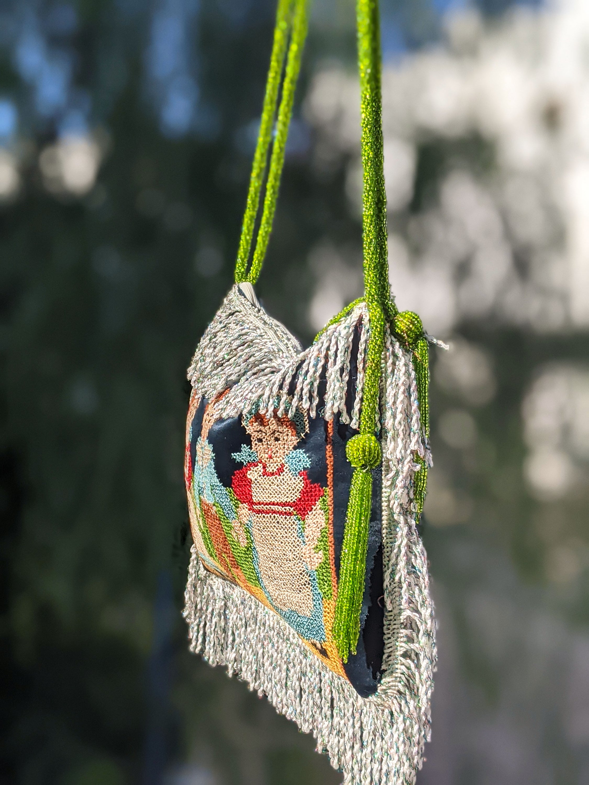 Antique garment cloth bag featuring hand-embroidered peasant figures and green beaded cord handles, showcasing intricate craftsmanship.