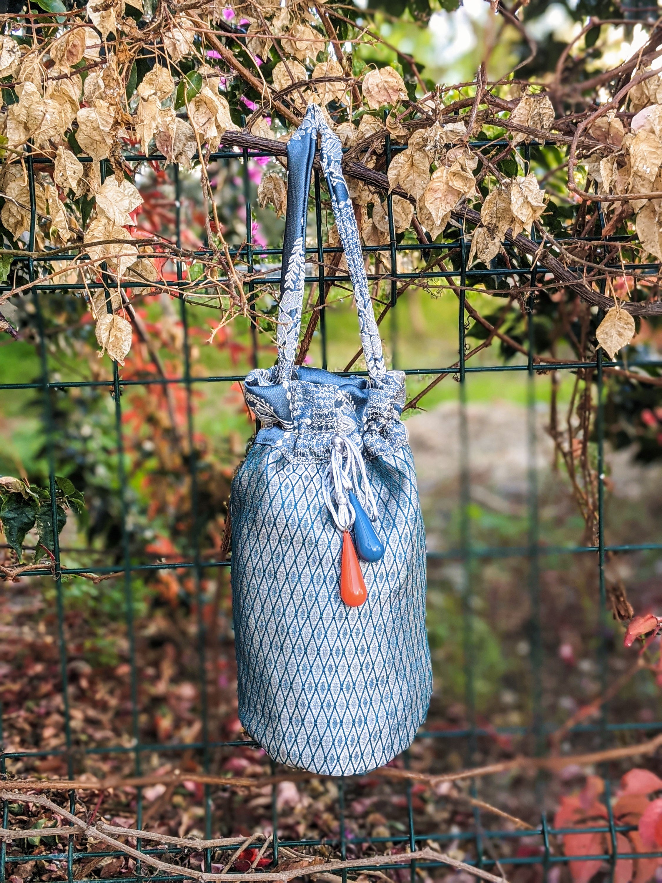 Navy blue pouch shoulder bag with decorative blue and orange glass beads and a jacquard fabric handle.