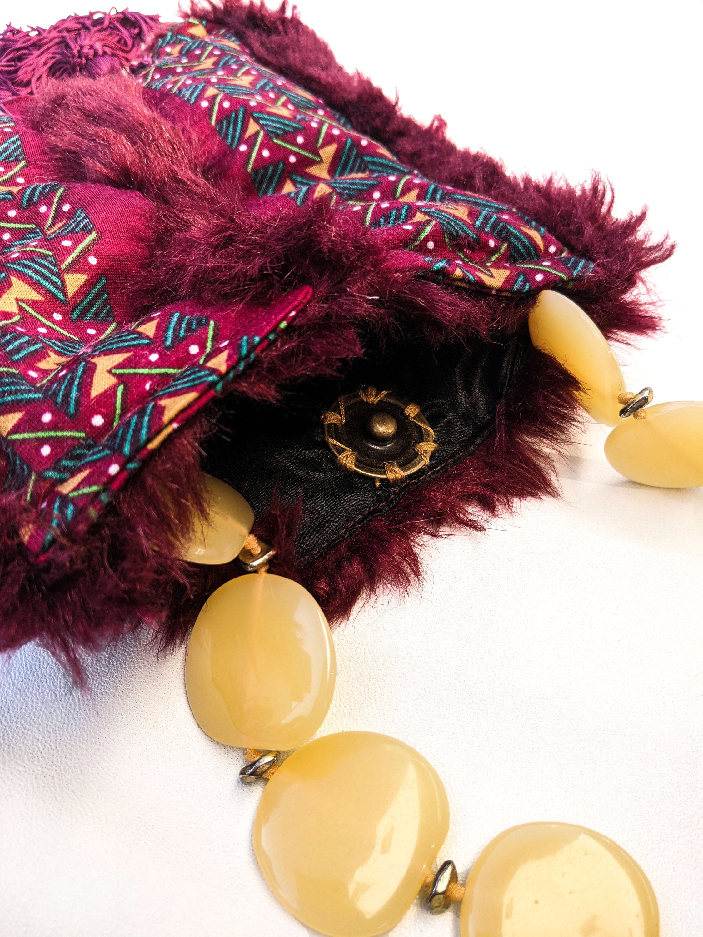 Stylish burgundy fur bag with tassels and yellow bead handle, showcasing unique Brecciated Jasper design.