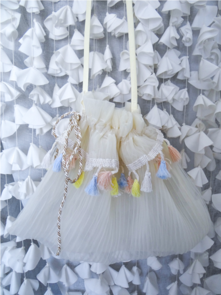 The BRIDE bag made from pleated chiffon, featuring colorful mini tassels and a shoulder strap, showcasing its modern and eco-friendly design.