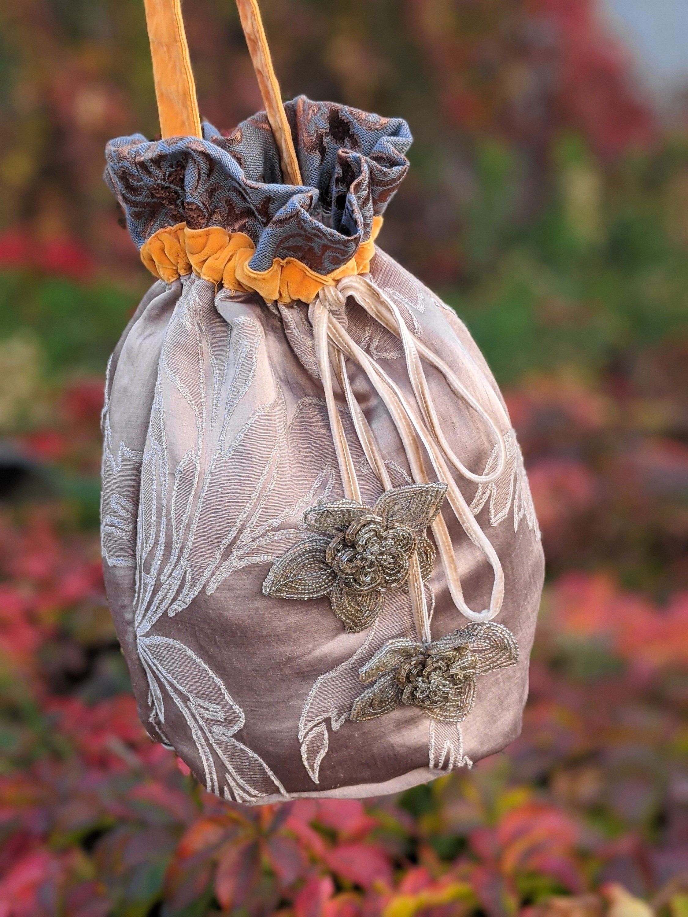 Bruneau Jasper cinch bag with self-embossed design and orange velvet handle, showcasing its stylish and functional features.