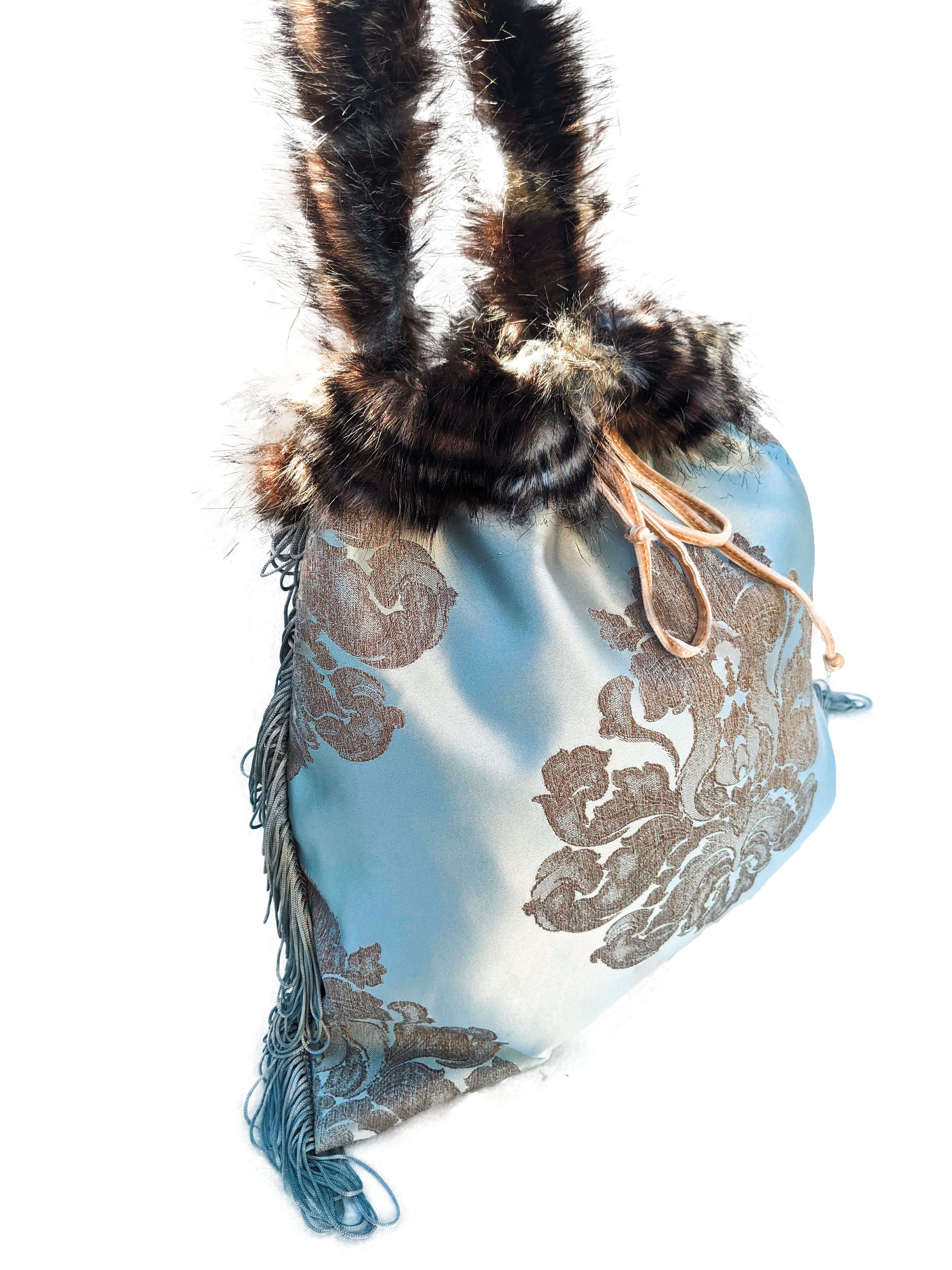 Dendritic Jasper pouch bag featuring silvery blue sateen, faux fur handle, grey fringes, and cream velvet string closure.