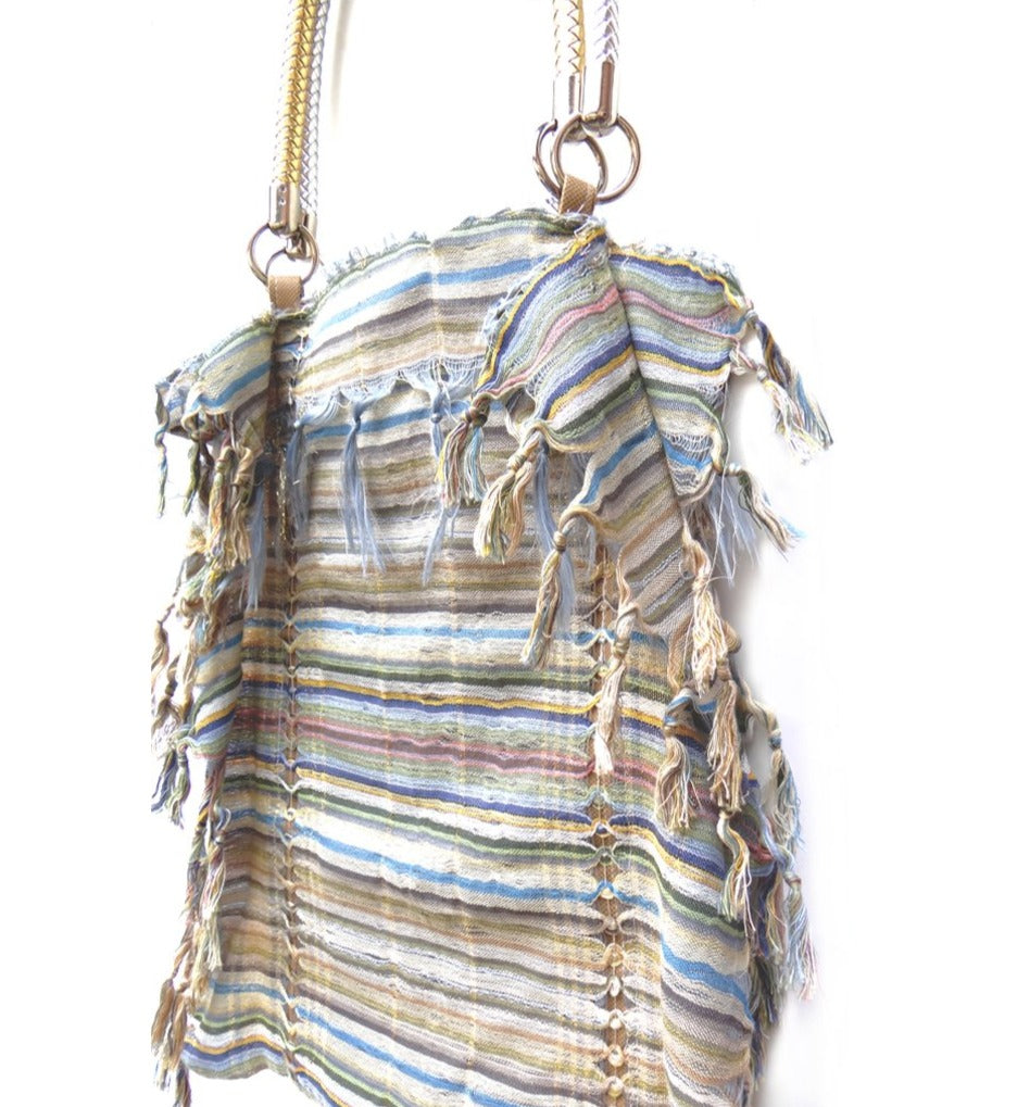 A stylish self-fringed garment named FRINGY, featuring silver and gold handle accessories, showcasing modern upcycled fashion.