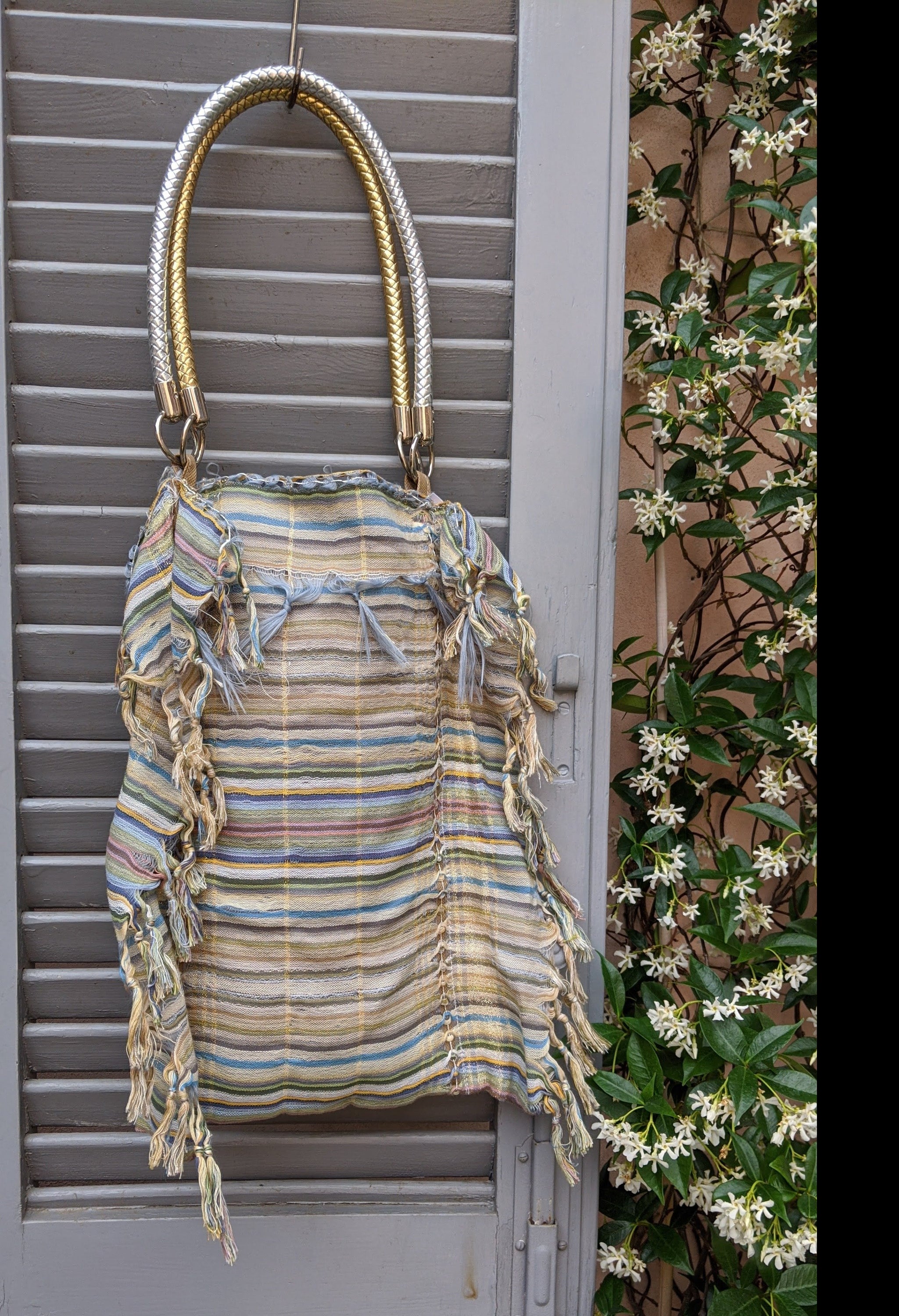 A stylish self-fringed garment named FRINGY, featuring silver and gold handle accessories, showcasing modern upcycled fashion.