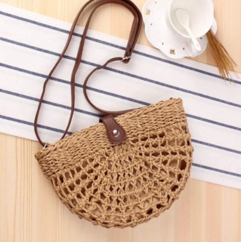 Half Moon Straw Crossbody Bag made of wicker straw with a vegan leather strap, featuring a trendy semi-circle design in brown color.