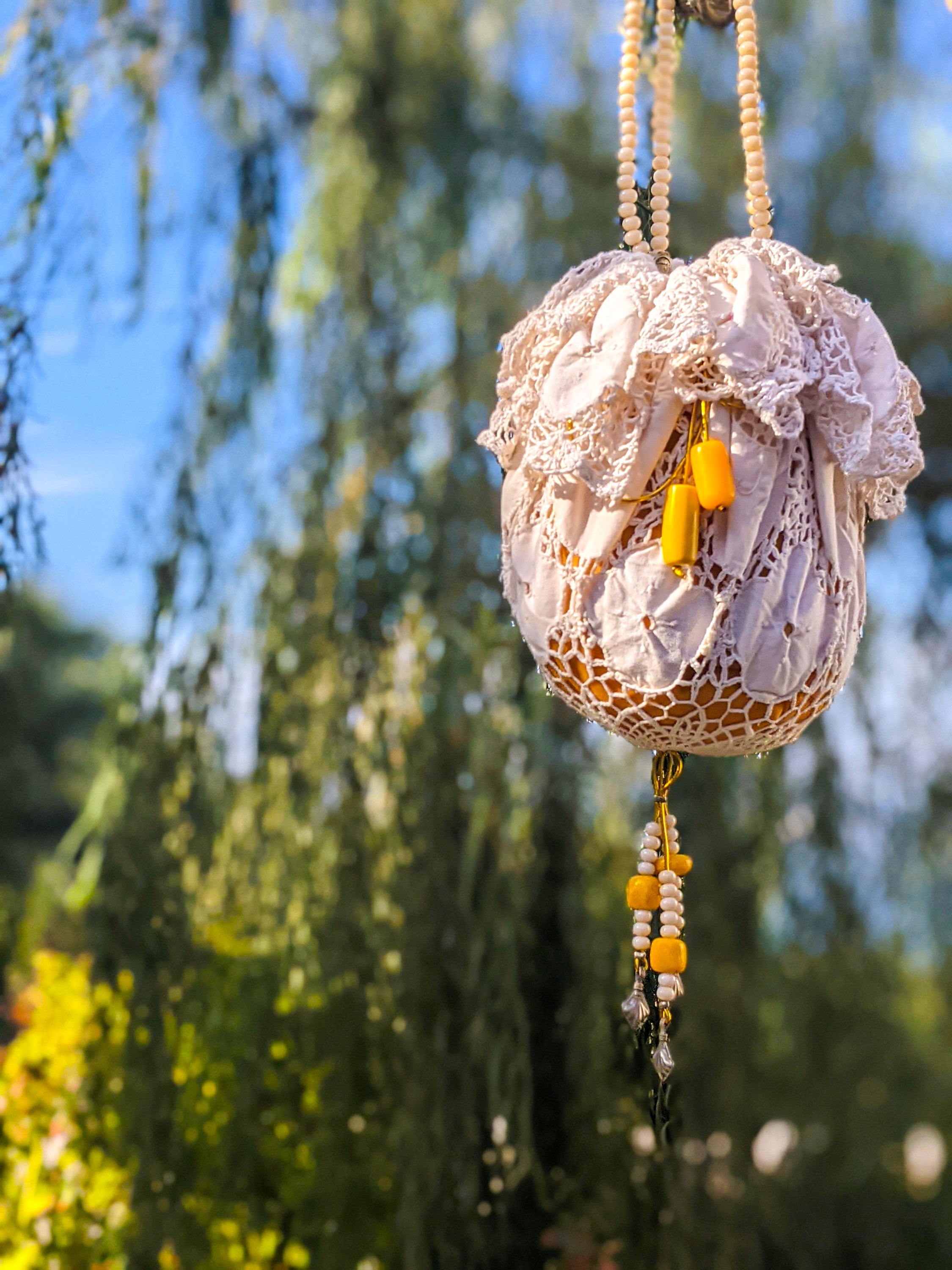 A beautifully crafted Handmade Lace Pouch Bag featuring intricate lacework, tulle lining, and a handle adorned with rosary and resin beads.