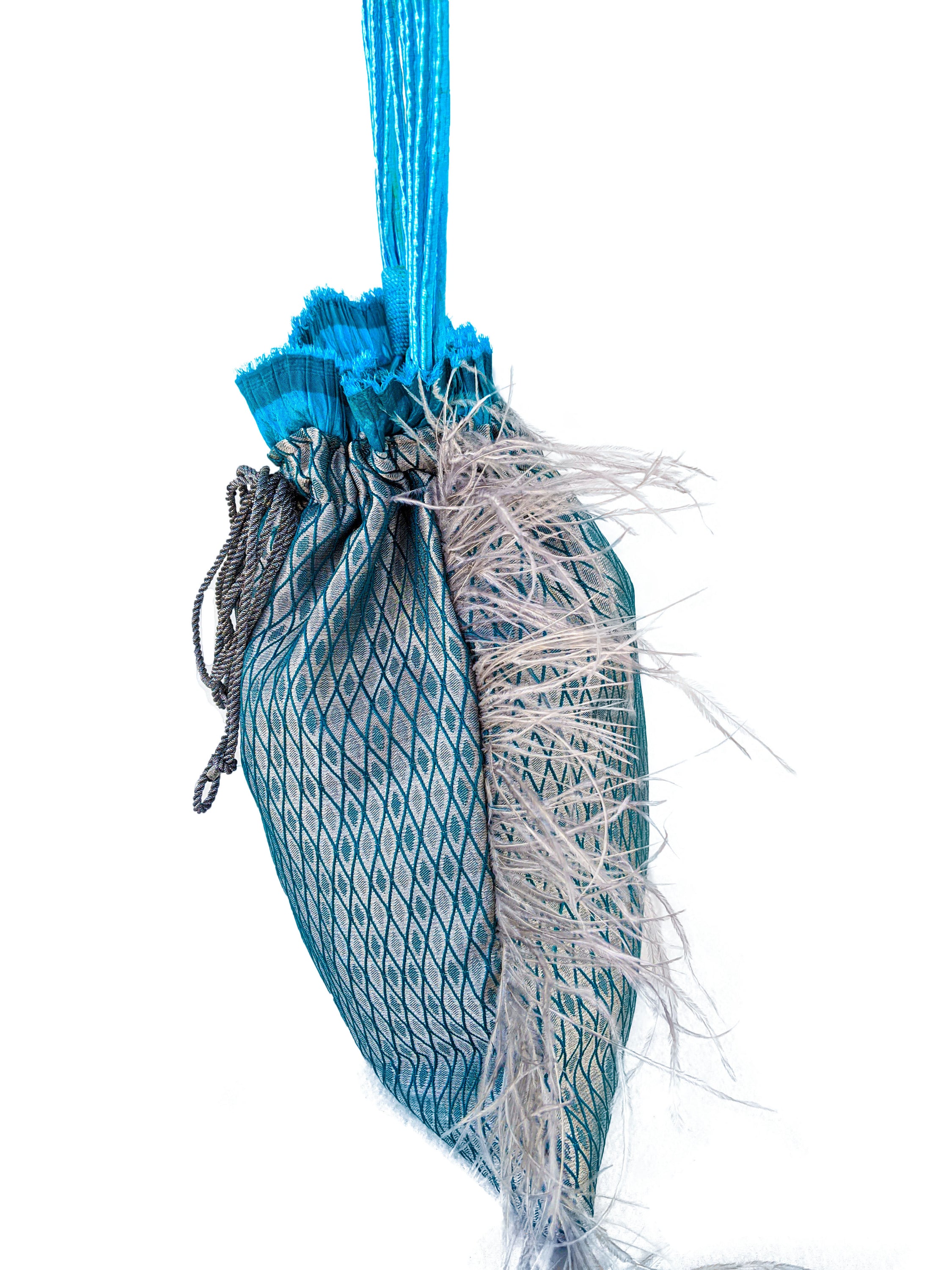 Imperial Jasper pouch bag featuring silvery blue fabric, turquoise accordion detail, grey feathers, and raffia cord handle.