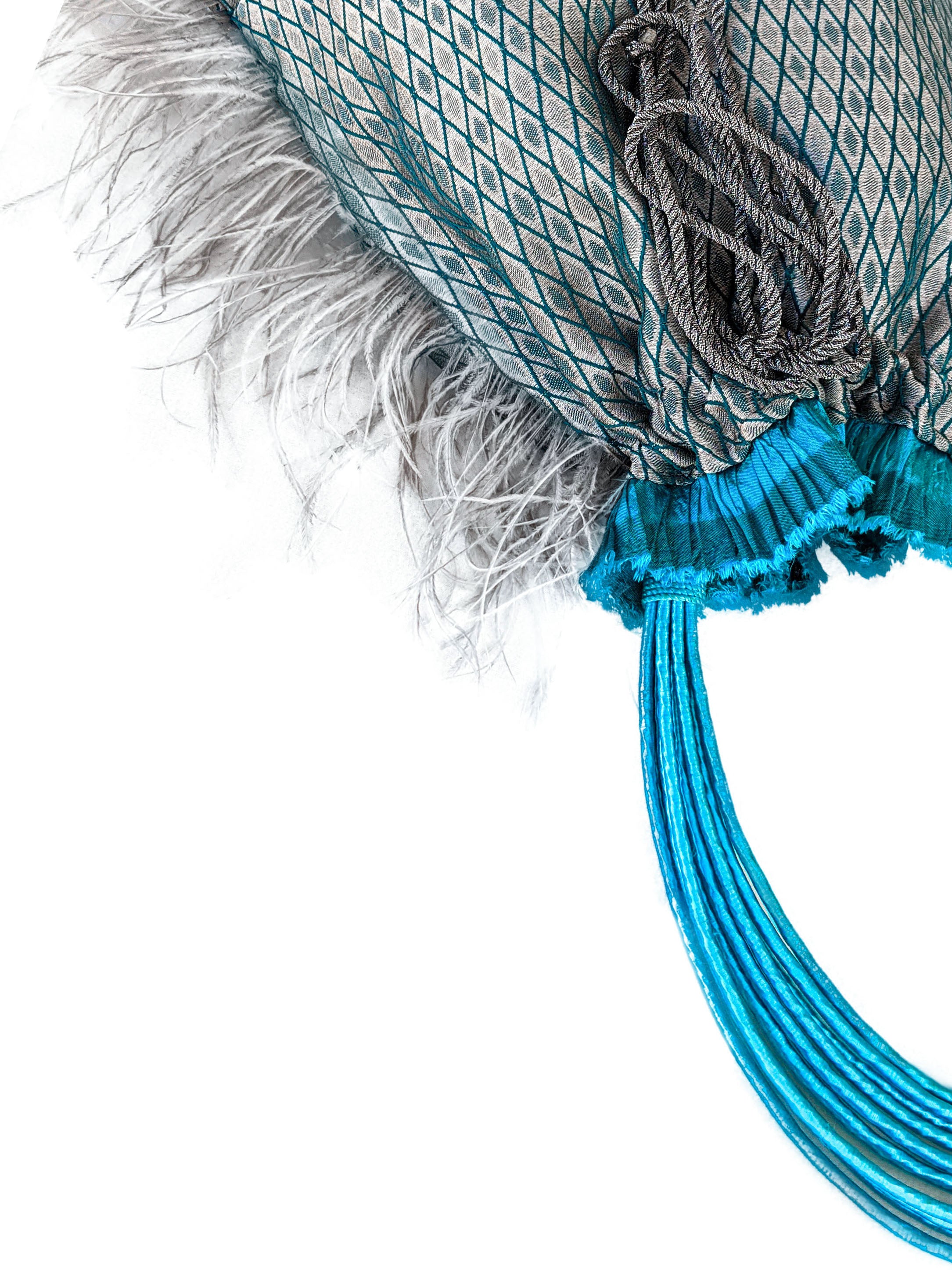 Imperial Jasper pouch bag featuring silvery blue fabric, turquoise accordion detail, grey feathers, and raffia cord handle.