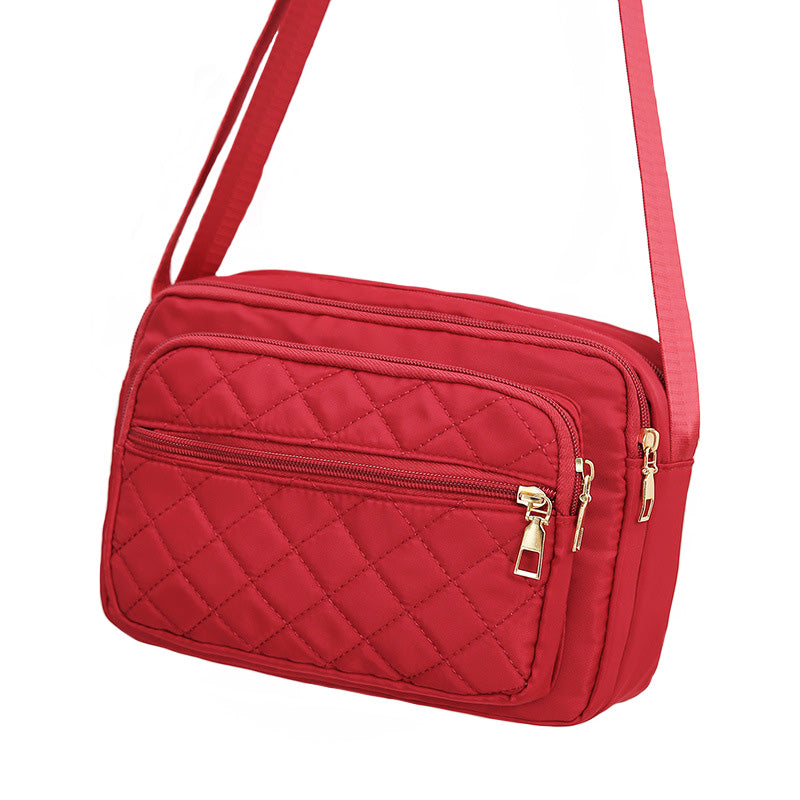 Ladies' Nylon Quilted Bag featuring a stylish quilted design, multiple zipper pockets, and an adjustable strap for versatile use.