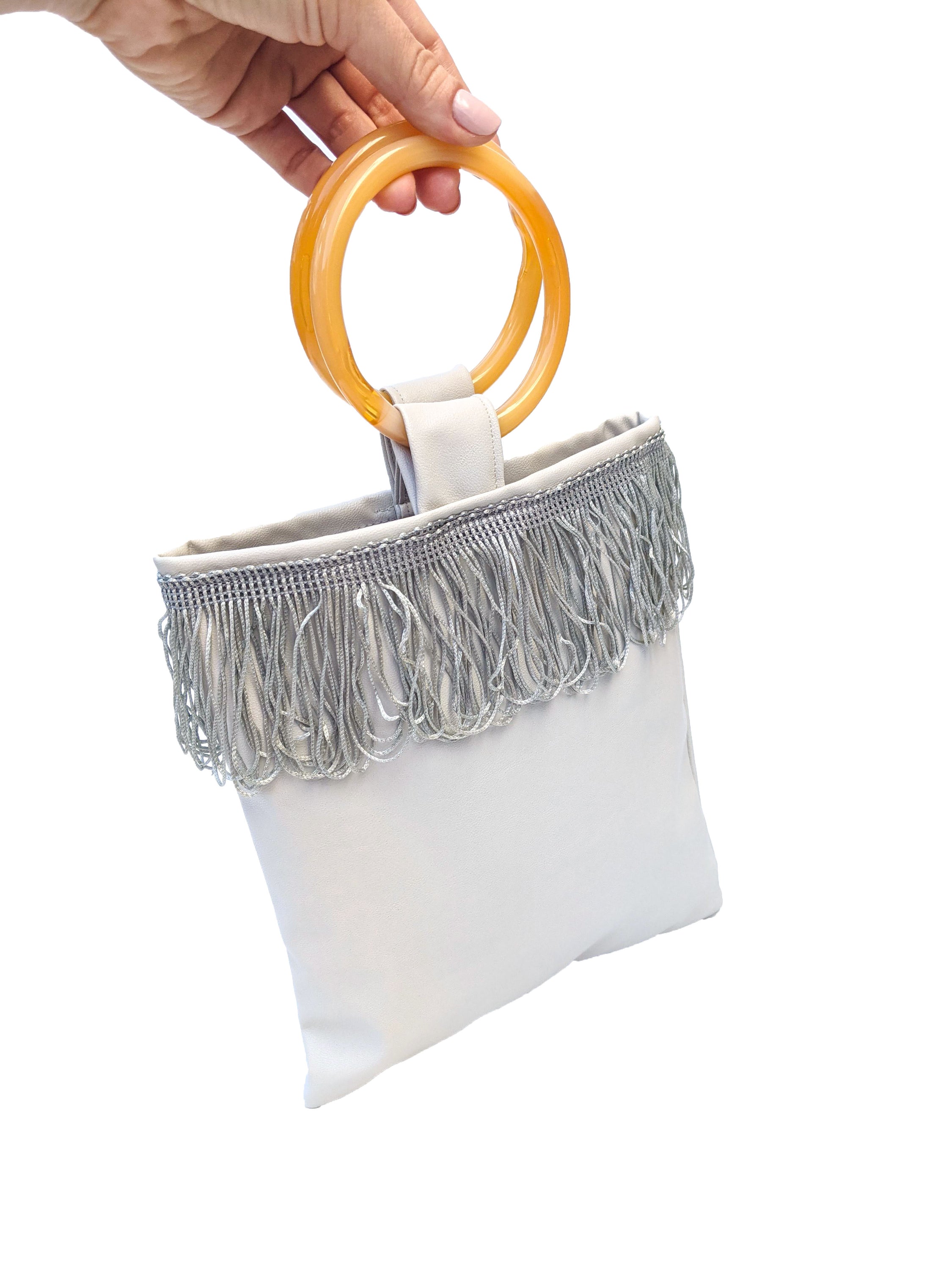 Light grey mini faux leather bag with amber resin handles and grey fringes, showcasing a stylish and compact design.